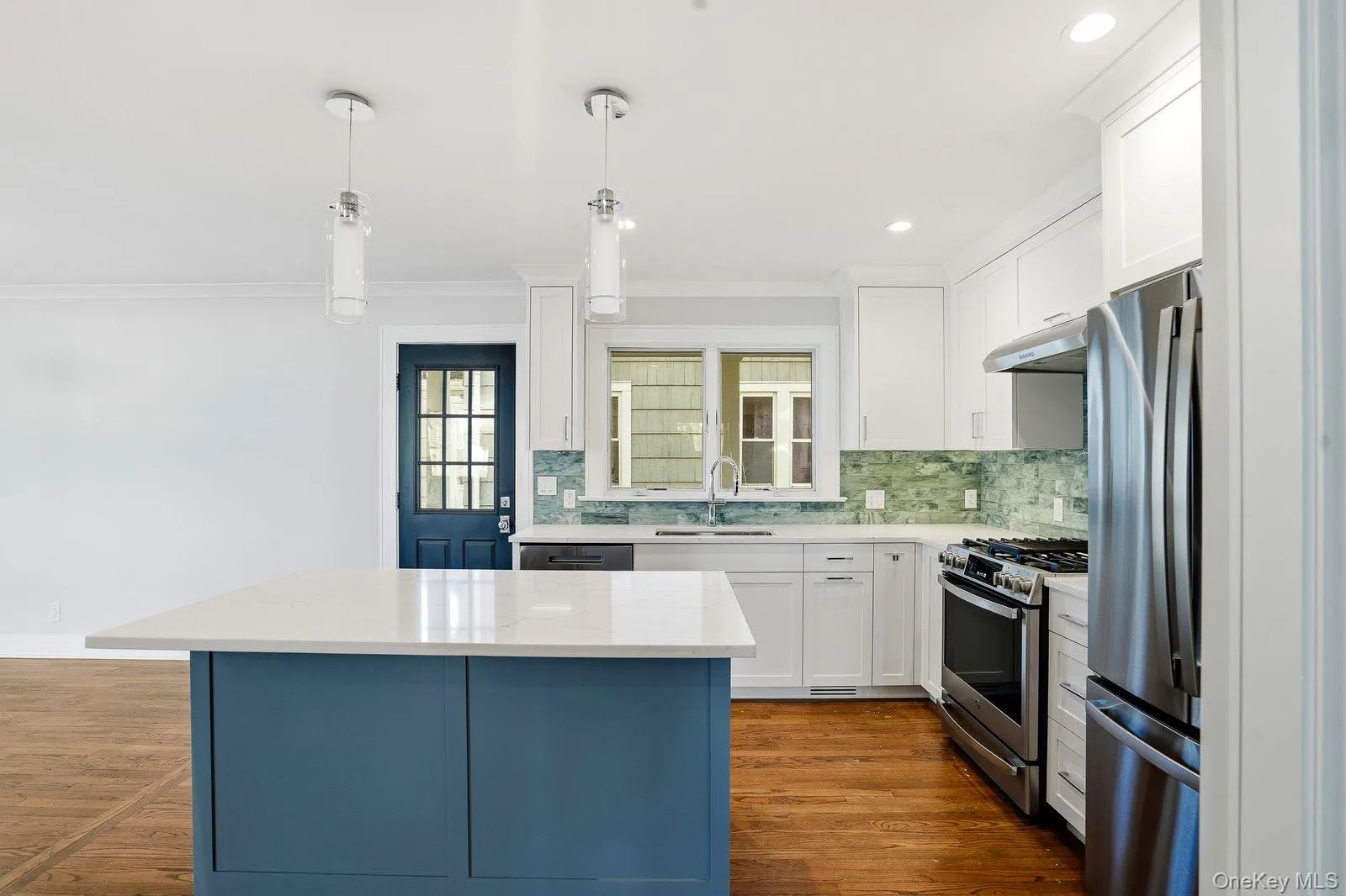 Kitchen with stainless steel finishes, white cabinets, light stone countertops, and dark wood finished floors Kitchen with stainless steel finishes, white cabinets, light stone countertops, and dark wood finished floors