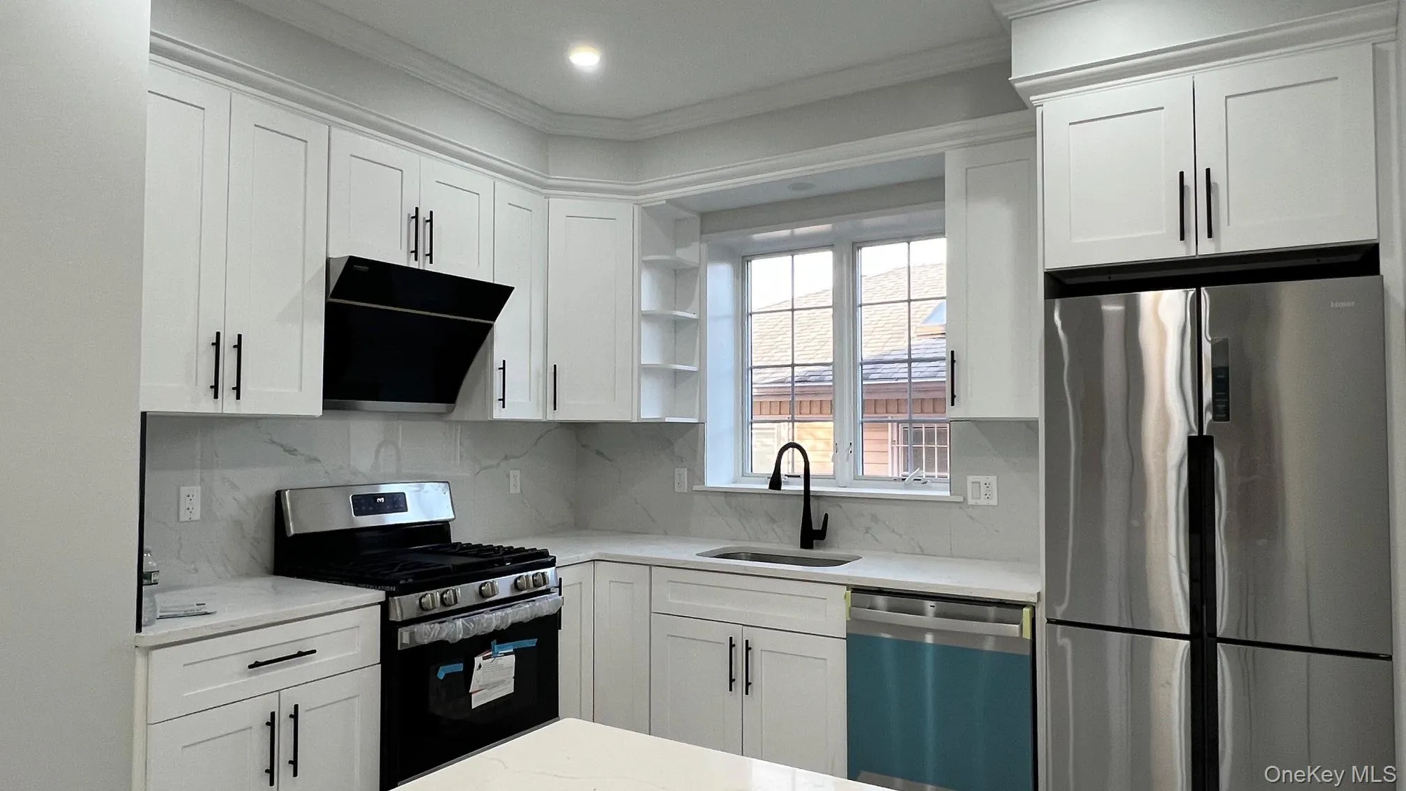 Kitchen with appliances with stainless steel finishes, white cabinetry, light stone counters, open shelves, and range hood Kitchen with appliances with stainless steel finishes, white cabinetry, light stone counters, open shelves, and range hood