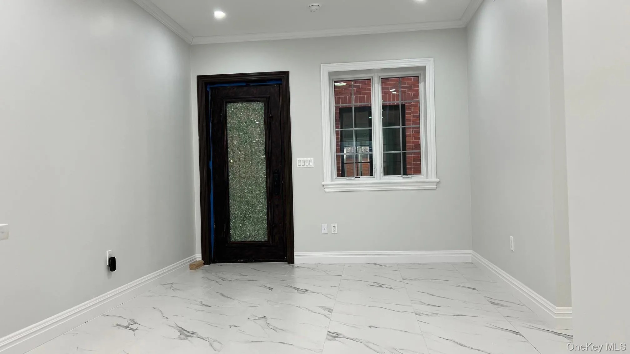 Foyer entrance with light marble finish flooring, ornamental molding, and recessed lighting Foyer entrance with light marble finish flooring, ornamental molding, and recessed lighting