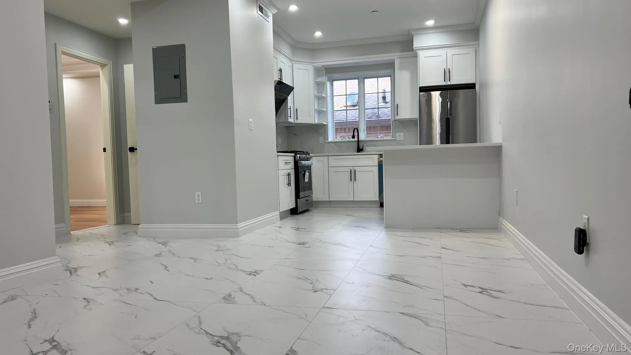 Kitchen with white cabinets, light marble finish floors, appliances with stainless steel finishes, light countertops, and electric panel Kitchen with white cabinets, light marble finish floors, appliances with stainless steel finishes, light countertops, and electric panel