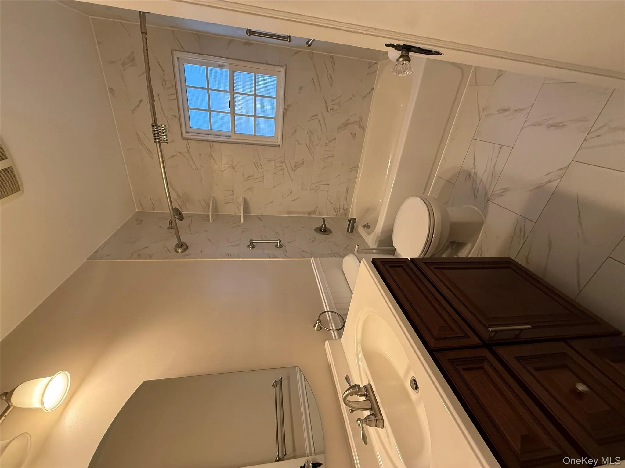 Bathroom featuring bathtub / shower combination, vanity, and light marble finish floors Bathroom featuring bathtub / shower combination, vanity, and light marble finish floors