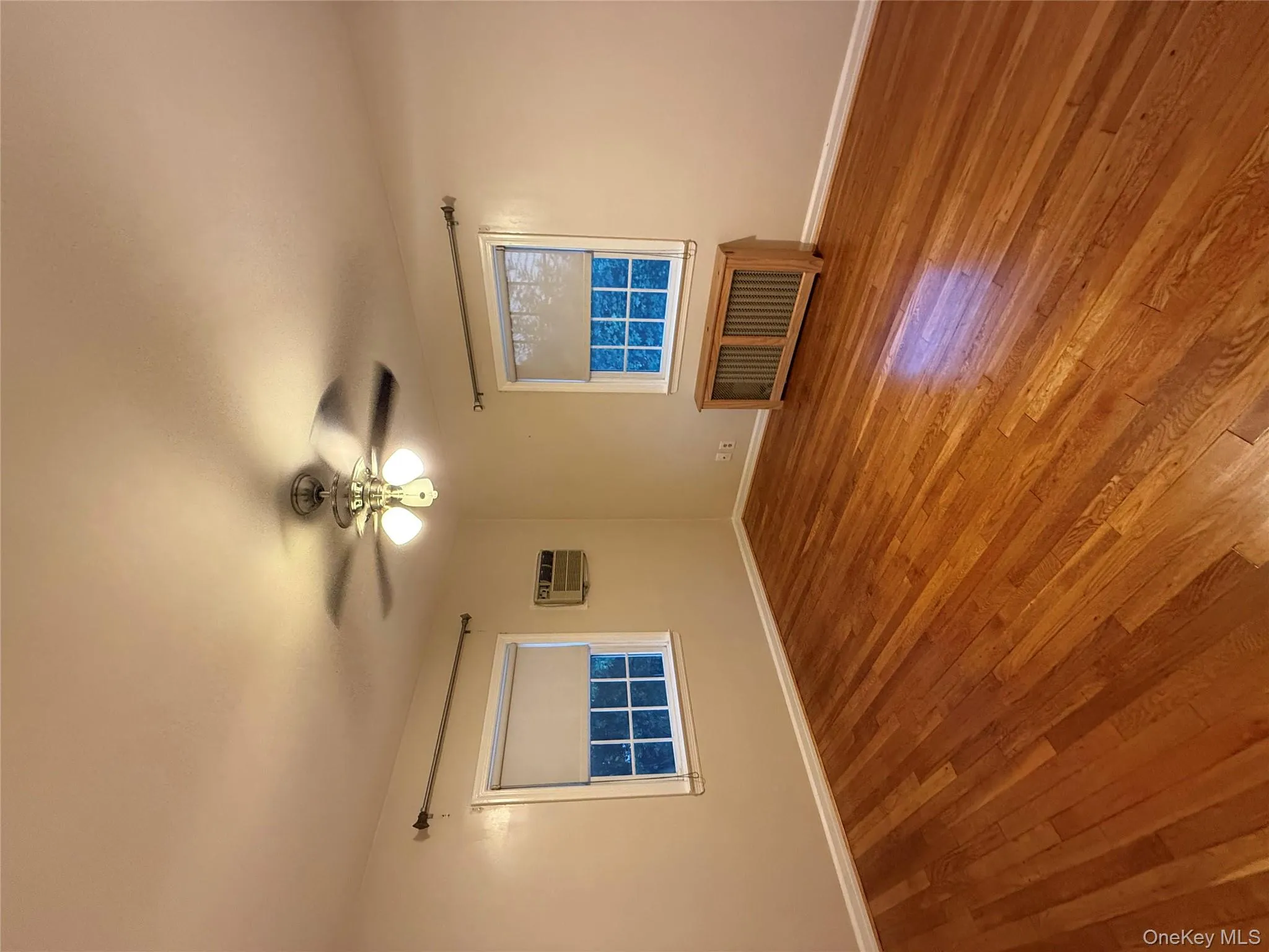 Empty room featuring radiator, hardwood / wood-style floors, and ceiling fan Empty room featuring radiator, hardwood / wood-style floors, and ceiling fan