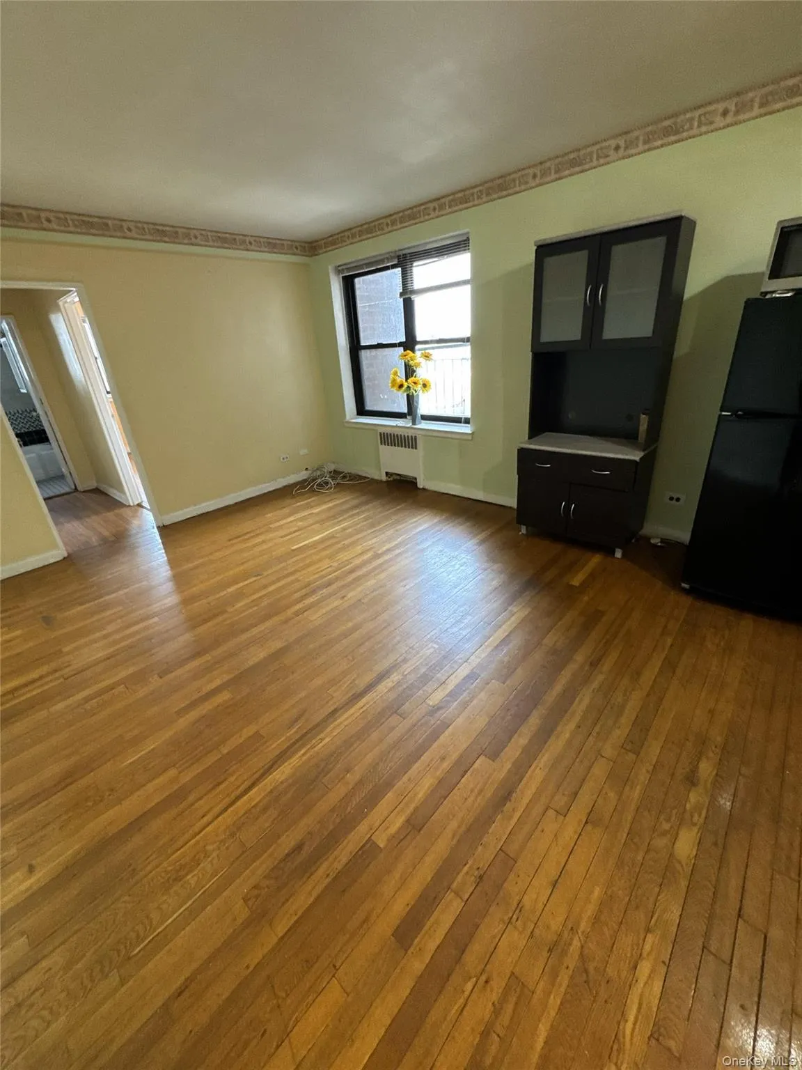 Unfurnished living room with dark wood-style flooring and radiator Unfurnished living room with dark wood-style flooring and radiator