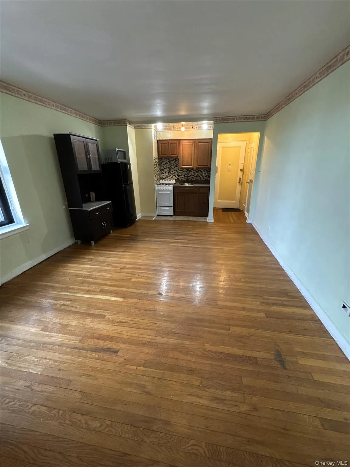 Kitchen with white range with gas stovetop, dark wood-type flooring, freestanding refrigerator, decorative backsplash, and crown molding Kitchen with white range with gas stovetop, dark wood-type flooring, freestanding refrigerator, decorative backsplash, and crown molding