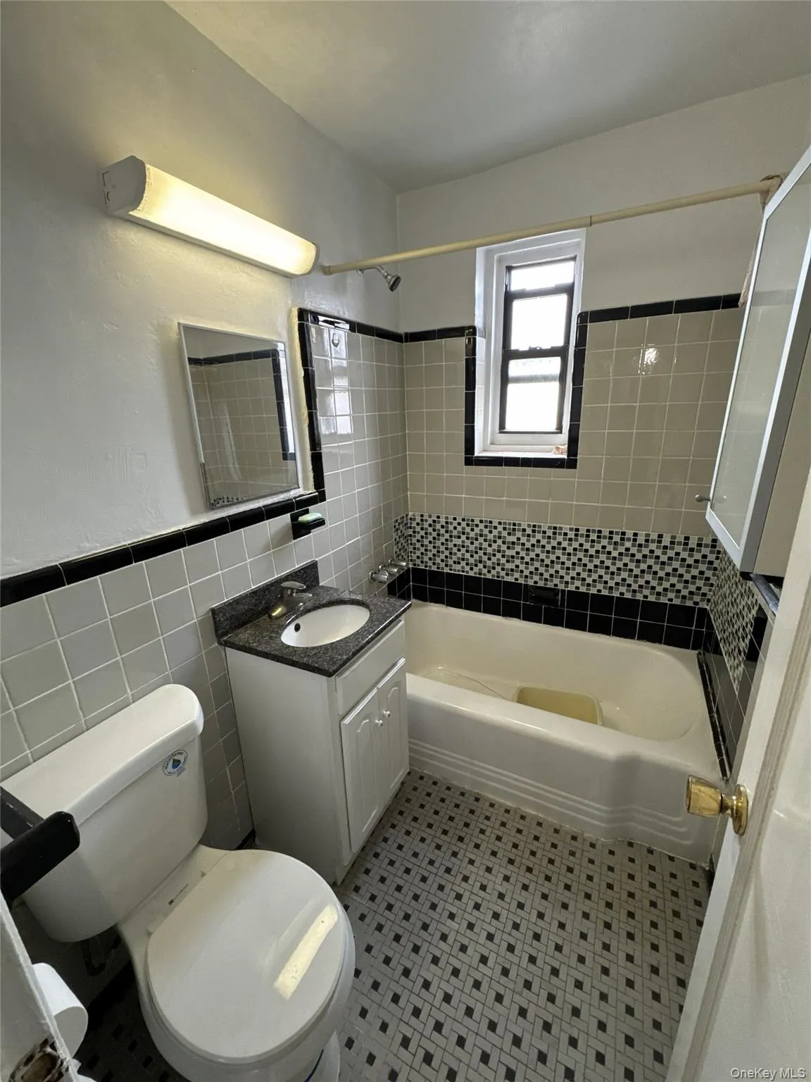 Full bathroom featuring vanity, tile walls, bathtub / shower combination, a wainscoted wall, and light flooring Full bathroom featuring vanity, tile walls, bathtub / shower combination, a wainscoted wall, and light flooring