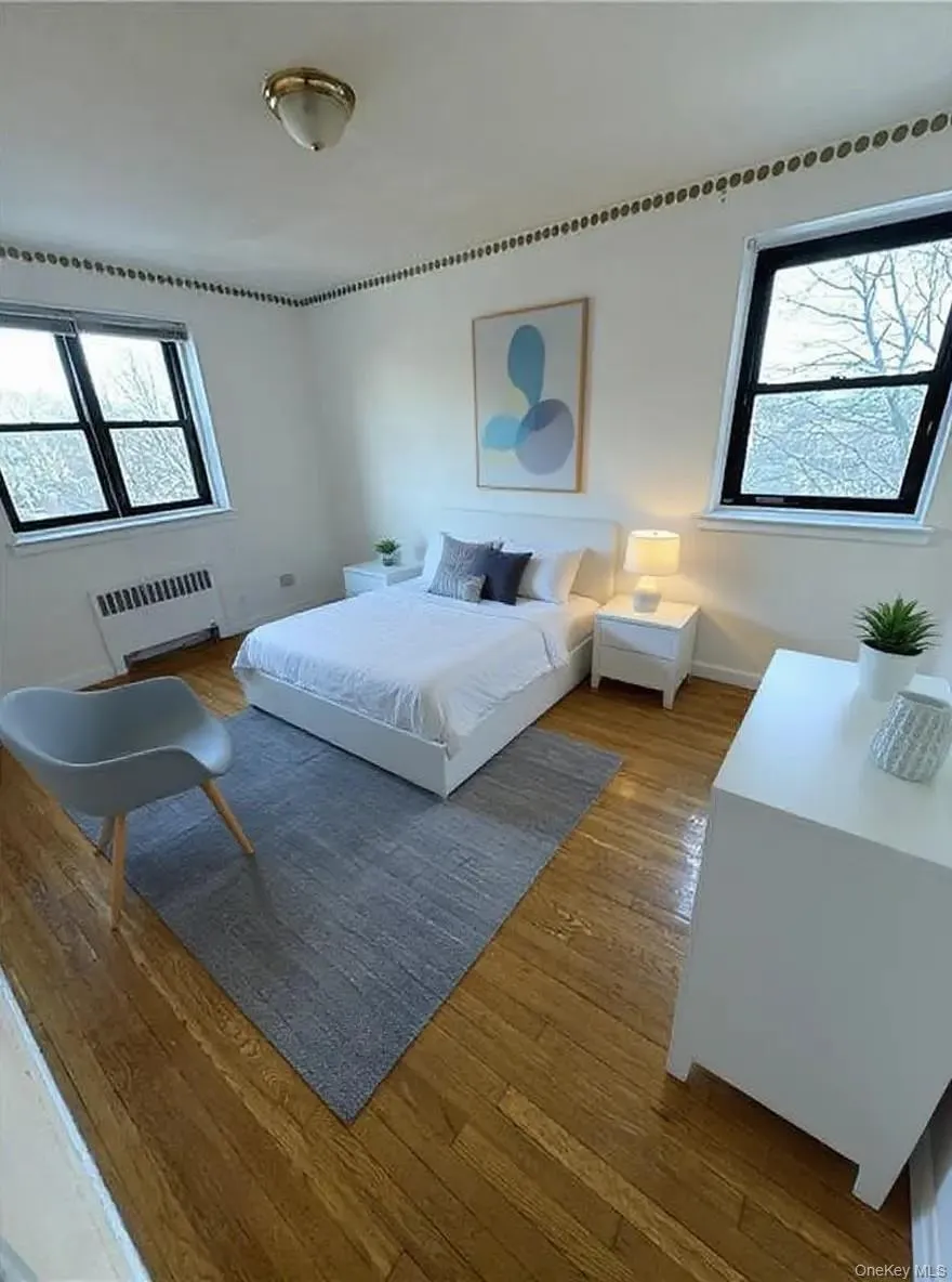 Bedroom featuring radiator heating unit and wood-type flooring Bedroom featuring radiator heating unit and wood-type flooring