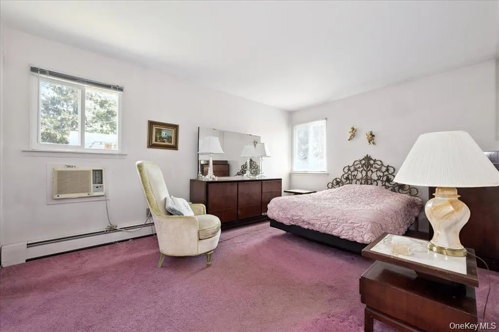 Bedroom with a baseboard heating unit, carpet, and a wall mounted AC Bedroom with a baseboard heating unit, carpet, and a wall mounted AC