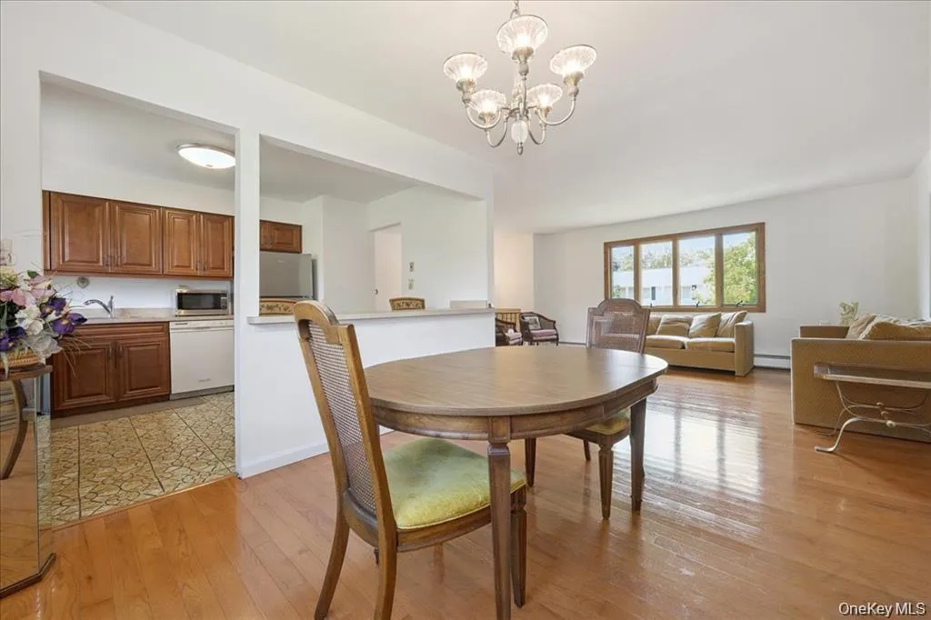 Dining room with a chandelier, light wood-style flooring, and baseboard heating Dining room with a chandelier, light wood-style flooring, and baseboard heating