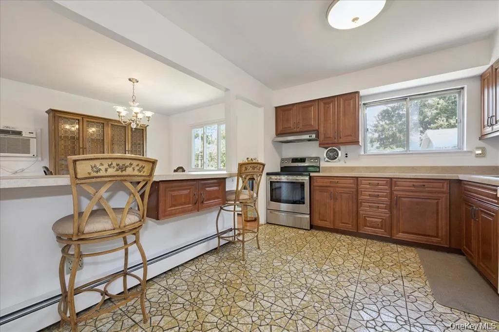 Kitchen featuring baseboard heating, electric range, light flooring, a chandelier, and light countertops Kitchen featuring baseboard heating, electric range, light flooring, a chandelier, and light countertops