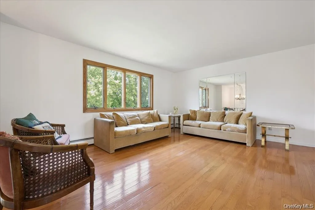 Living room featuring light wood-type flooring, a chandelier, and a baseboard radiator Living room featuring light wood-type flooring, a chandelier, and a baseboard radiator