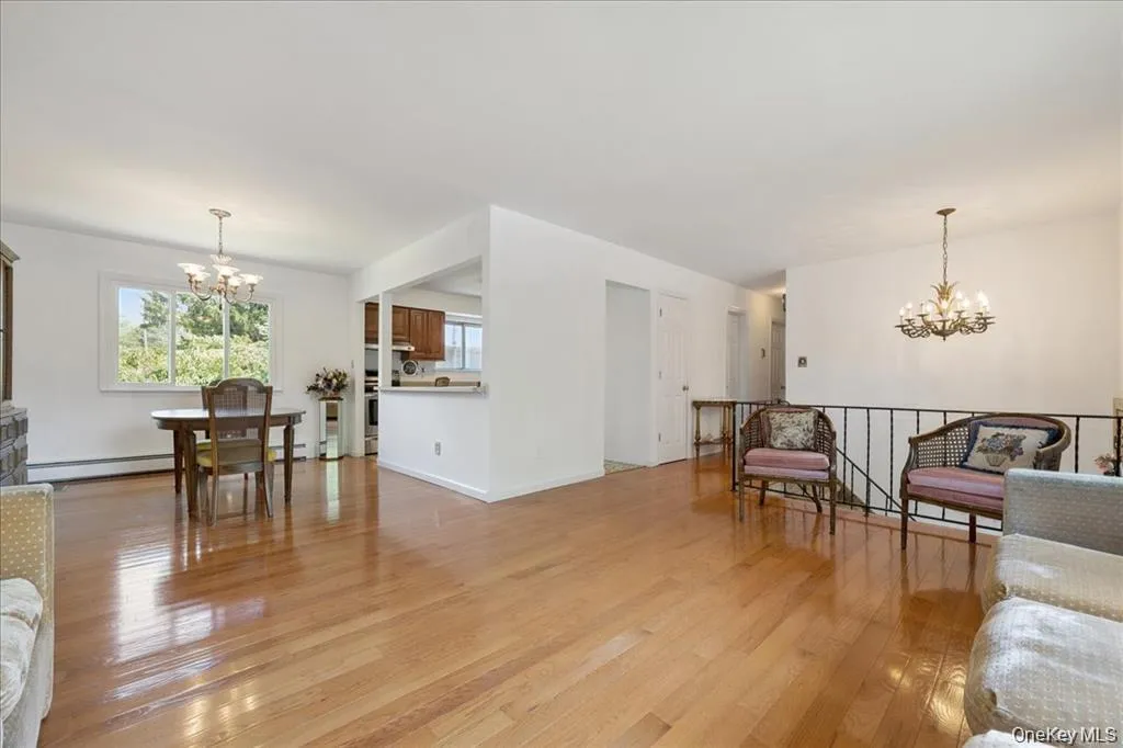 Living room with a chandelier, light wood finished floors, and a baseboard radiator Living room with a chandelier, light wood finished floors, and a baseboard radiator