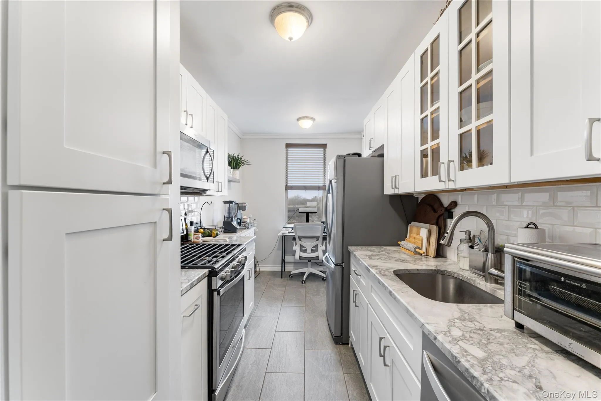 Fully renovated kitchen with custom-cut natural stone counters and stainless steel appliances, with eat-in nook under window, viewed from entry foyer Fully renovated kitchen with custom-cut natural stone counters and stainless steel appliances, with eat-in nook under window, viewed from entry foyer