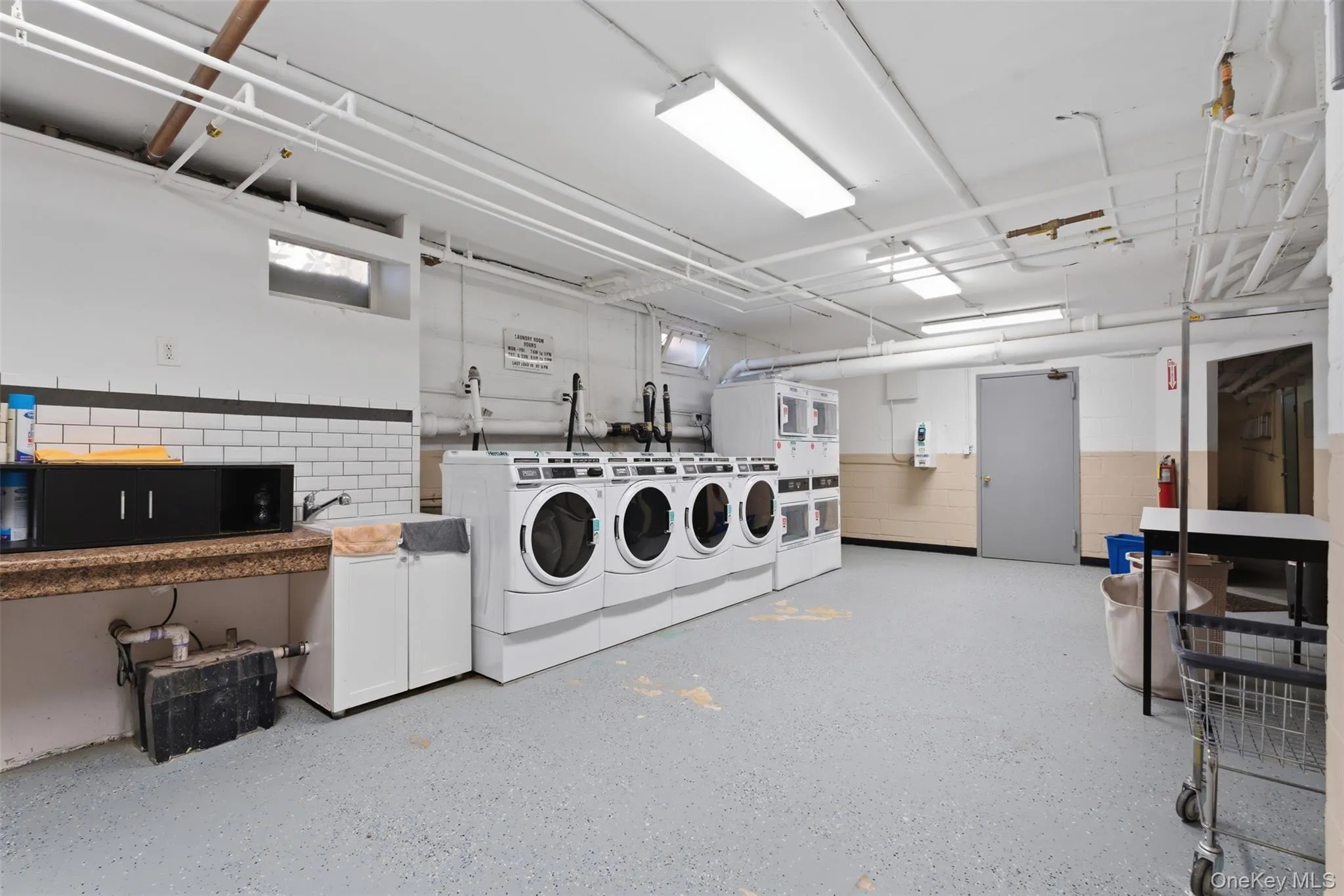 Dedicated laundry facility featuring several washing machines and dryers, a utility sink, and ample counter space for convenience. Machines operated by card. Dedicated laundry facility featuring several washing machines and dryers, a utility sink, and ample counter space for convenience. Machines operated by card.