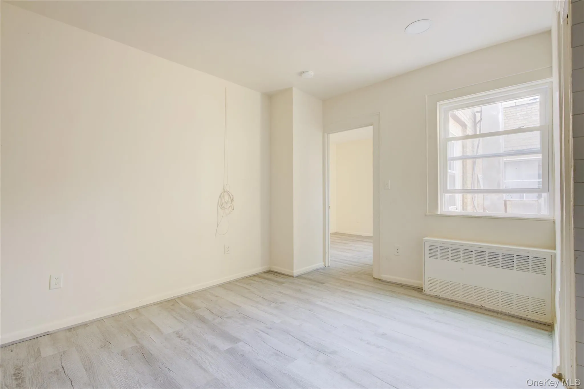 Unfurnished room featuring radiator and wood finished floors Unfurnished room featuring radiator and wood finished floors