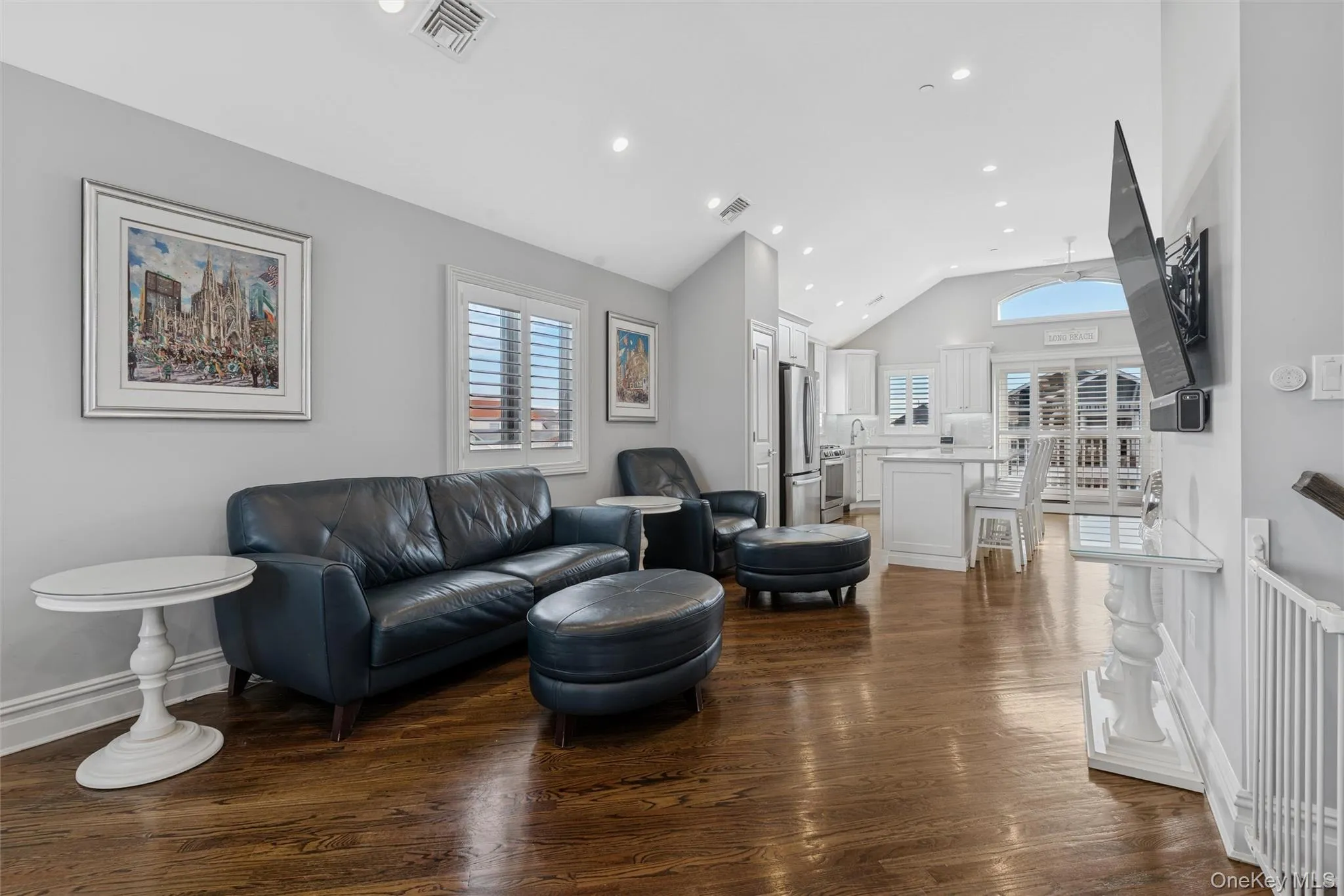 Living area with plenty of natural light, dark wood-style floors, lofted ceiling, and recessed lighting Living area with plenty of natural light, dark wood-style floors, lofted ceiling, and recessed lighting