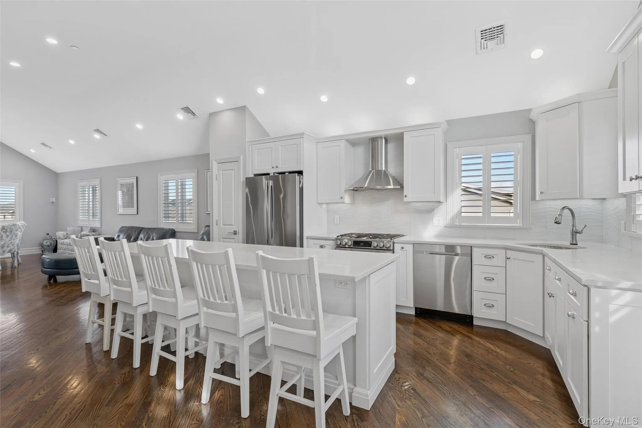 Kitchen with backsplash, white cabinets, a kitchen bar, a kitchen island, and lofted ceiling Kitchen with backsplash, white cabinets, a kitchen bar, a kitchen island, and lofted ceiling