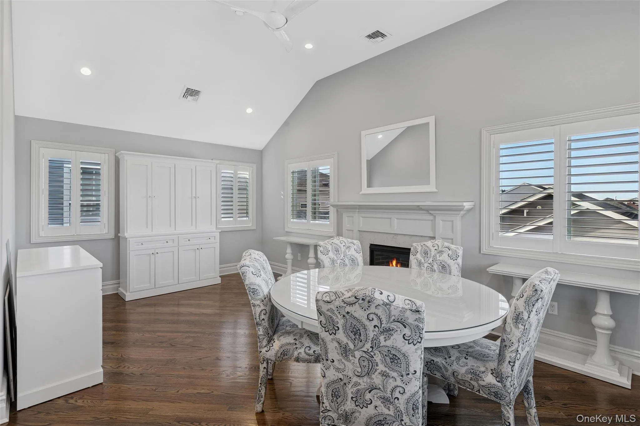 Dining space with a warm lit fireplace, dark wood finished floors, vaulted ceiling, and recessed lighting Dining space with a warm lit fireplace, dark wood finished floors, vaulted ceiling, and recessed lighting