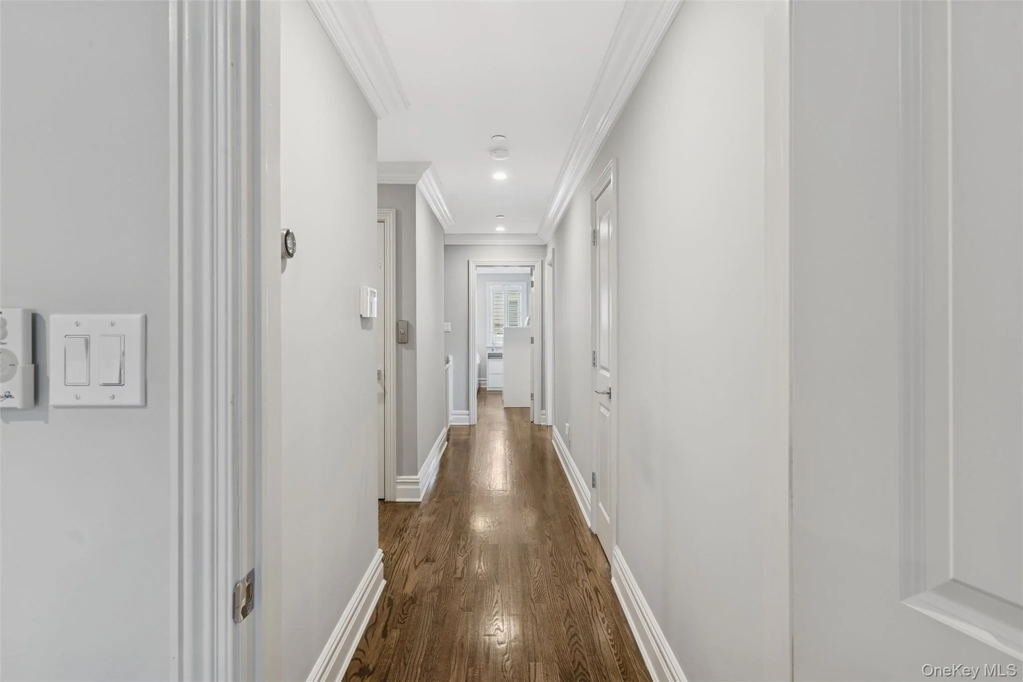 Corridor with dark wood-style flooring, ornamental molding, and recessed lighting Corridor with dark wood-style flooring, ornamental molding, and recessed lighting