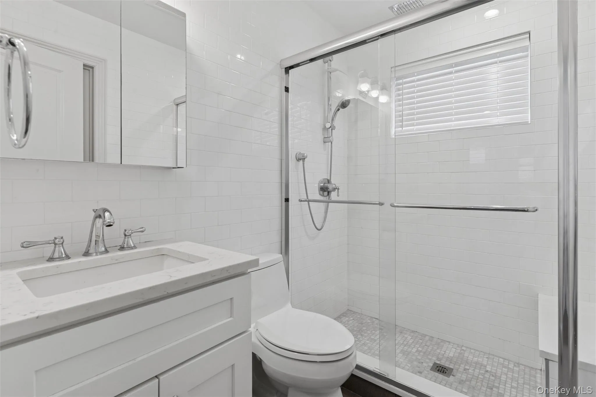 Full bath featuring tile walls, vanity, a stall shower, and decorative backsplash Full bath featuring tile walls, vanity, a stall shower, and decorative backsplash