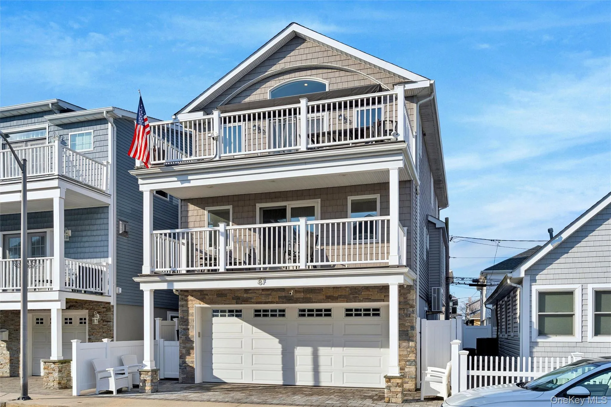View of front of home featuring stone siding, a balcony, driveway, and an attached garage View of front of home featuring stone siding, a balcony, driveway, and an attached garage