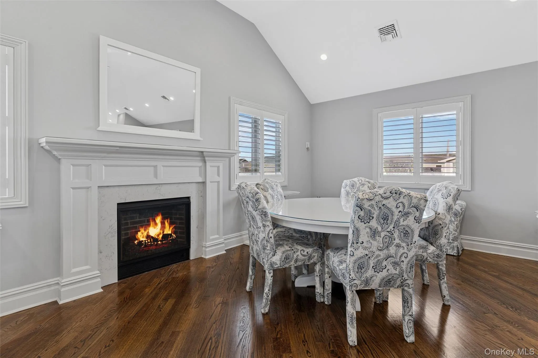 Dining room featuring vaulted ceiling, dark wood finished floors, a high end fireplace, and recessed lighting Dining room featuring vaulted ceiling, dark wood finished floors, a high end fireplace, and recessed lighting