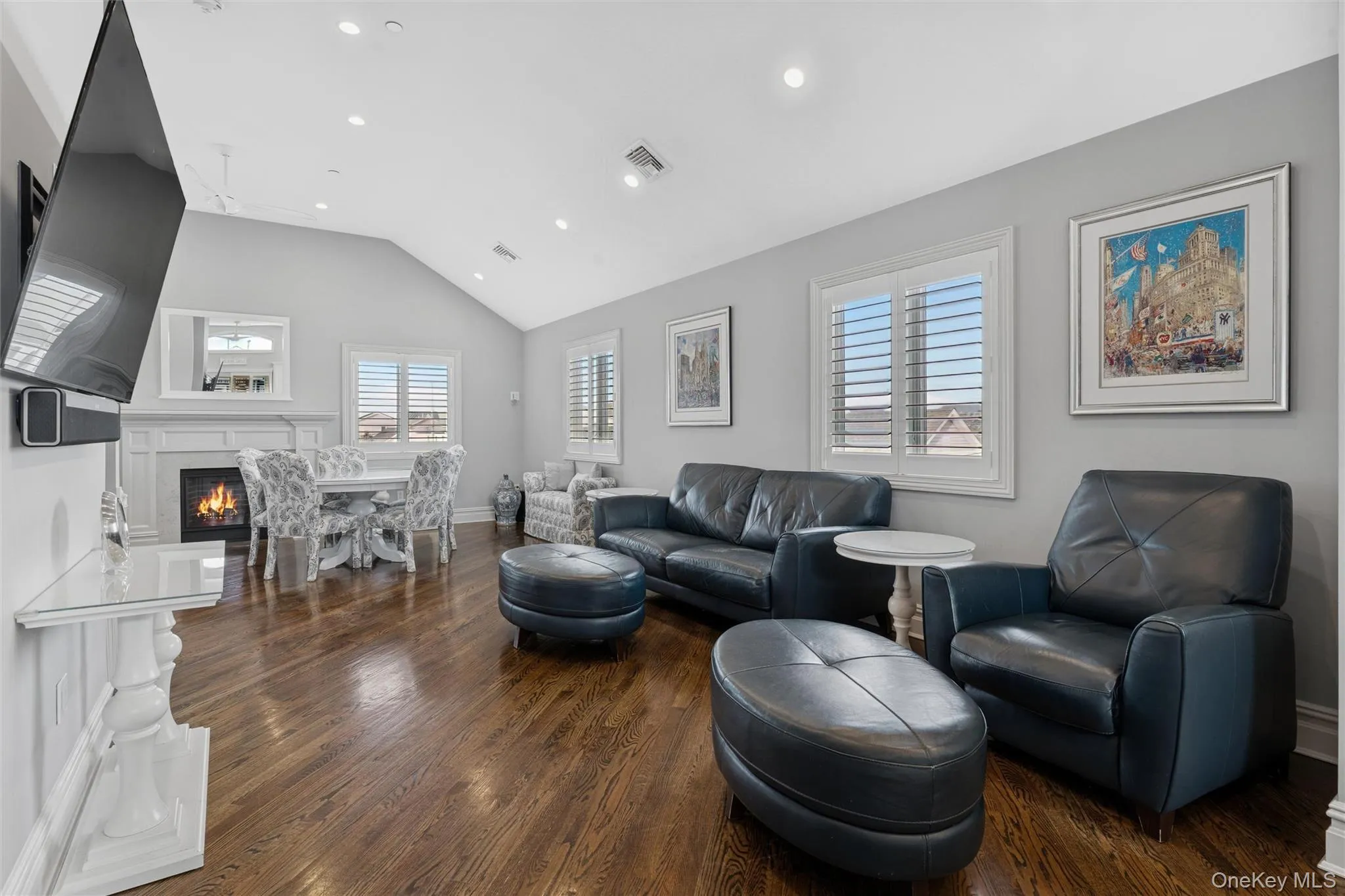 Living room featuring vaulted ceiling, a warm lit fireplace, dark wood-style flooring, healthy amount of natural light, and recessed lighting Living room featuring vaulted ceiling, a warm lit fireplace, dark wood-style flooring, healthy amount of natural light, and recessed lighting