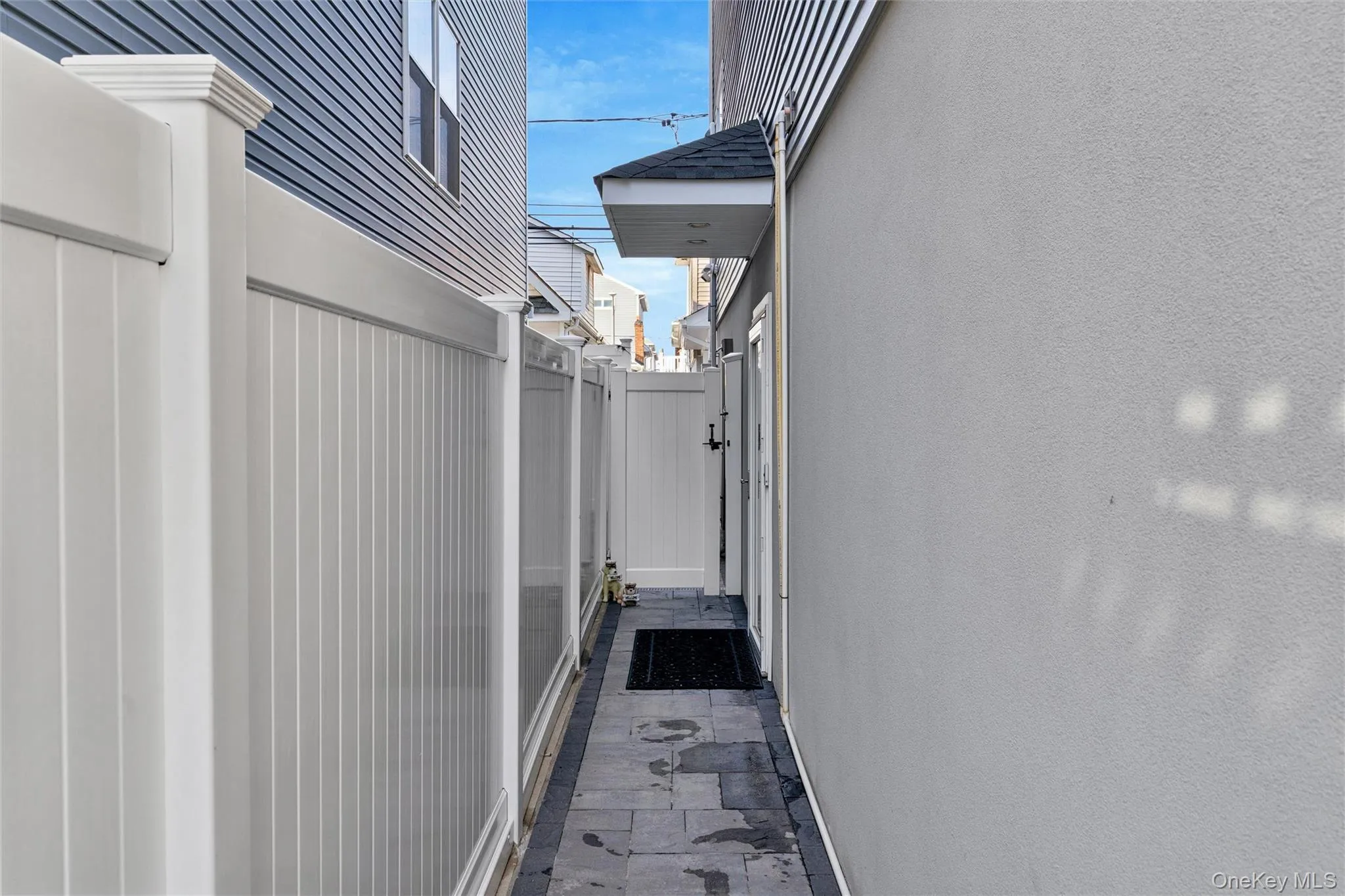View of side of home featuring stucco siding and a gate View of side of home featuring stucco siding and a gate