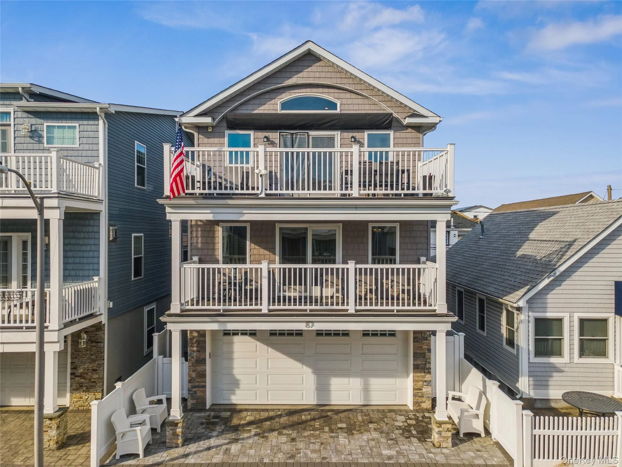 View of front of home with decorative driveway, stone siding, an attached garage, and a balcony View of front of home with decorative driveway, stone siding, an attached garage, and a balcony