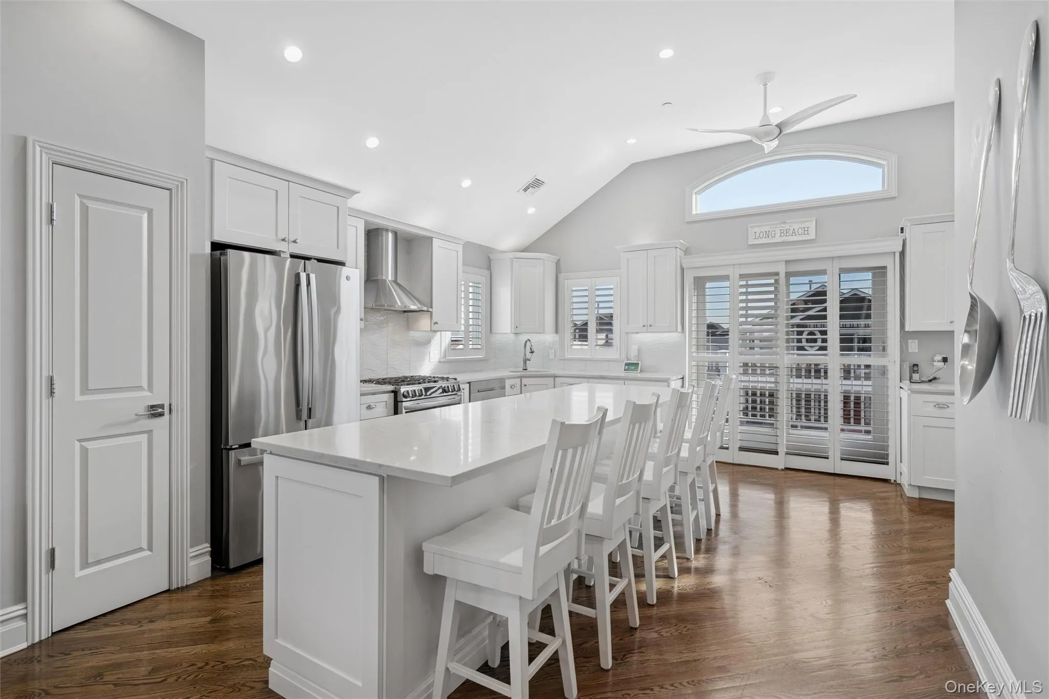 Kitchen with a breakfast bar area, white cabinets, appliances with stainless steel finishes, dark wood finished floors, and recessed lighting Kitchen with a breakfast bar area, white cabinets, appliances with stainless steel finishes, dark wood finished floors, and recessed lighting