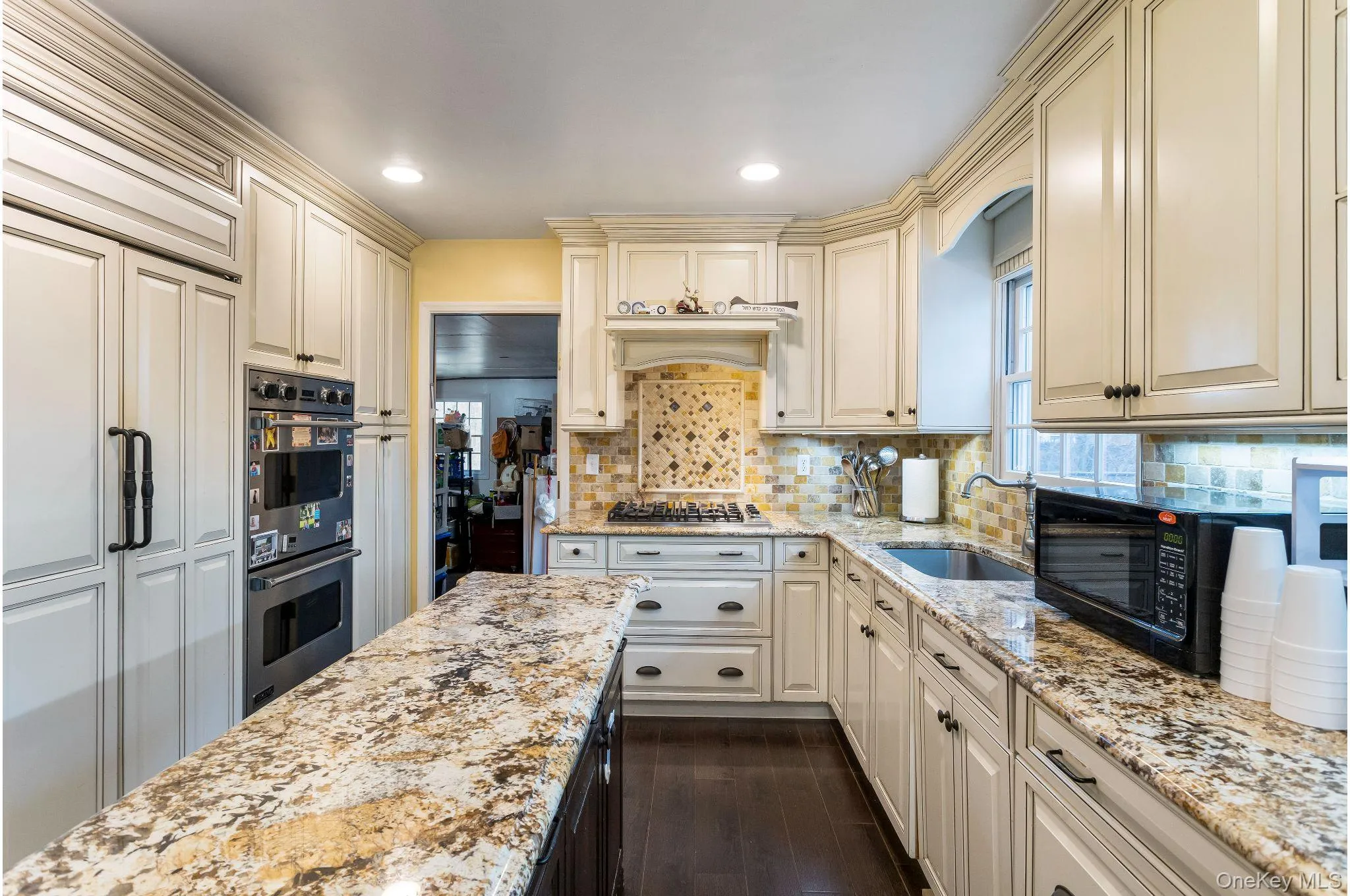 Kitchen with light granite counters, cream cabinetry, appliances with stainless steel finishes, recessed lighting, and dark wood finished floors Kitchen with light granite counters, cream cabinetry, appliances with stainless steel finishes, recessed lighting, and dark wood finished floors