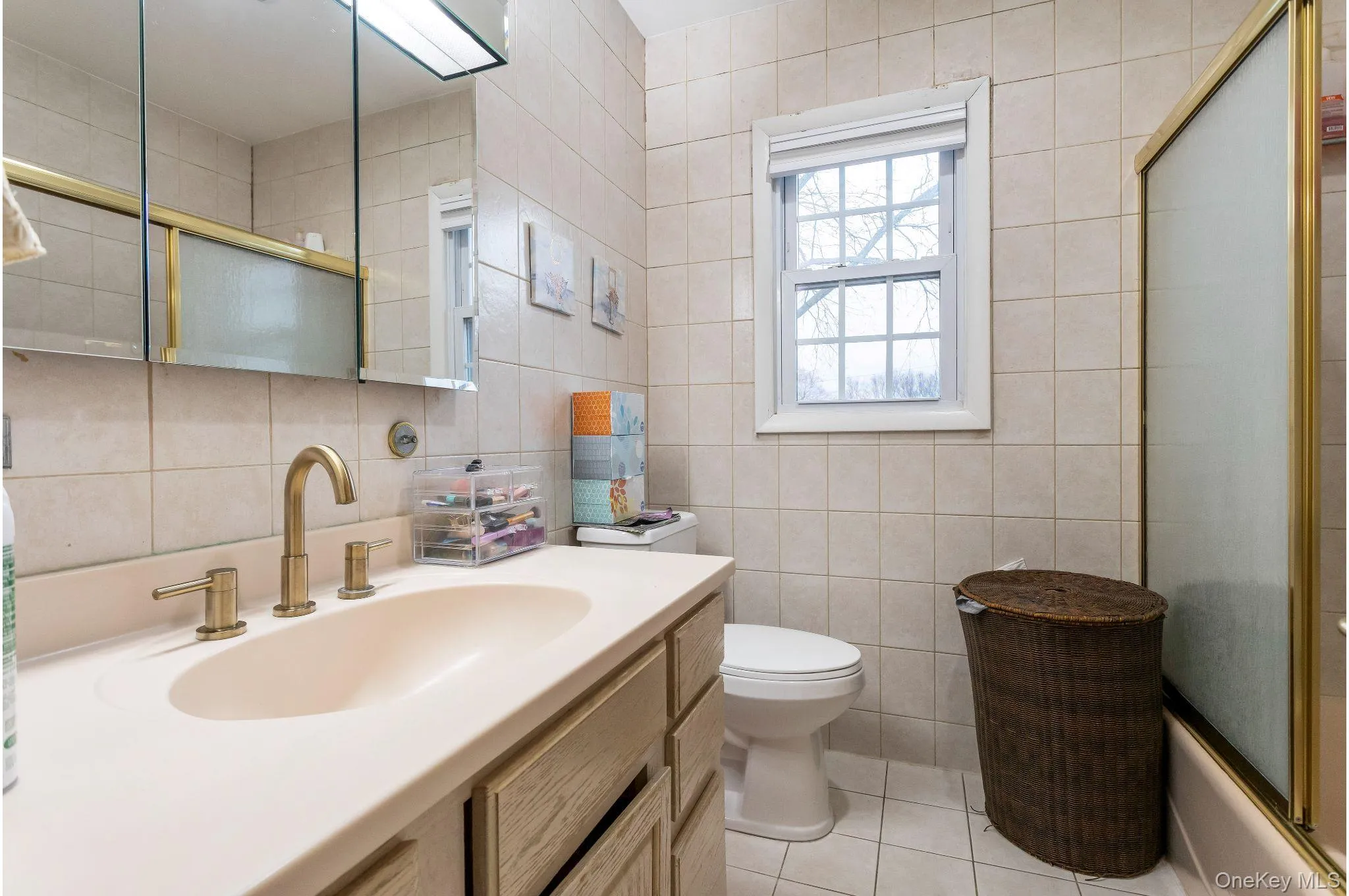 Full bathroom featuring vanity, combined bath / shower with glass door, tile walls, and light tile patterned floors Full bathroom featuring vanity, combined bath / shower with glass door, tile walls, and light tile patterned floors