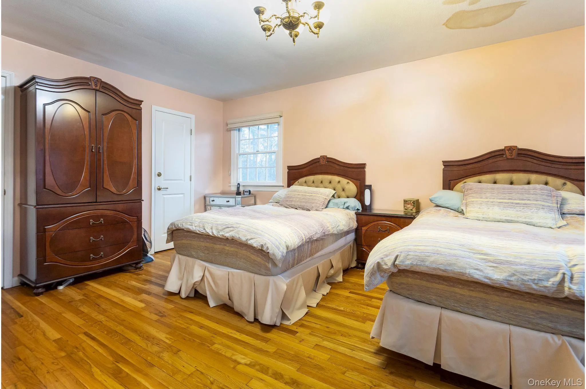 Bedroom featuring light wood-type flooring and a chandelier Bedroom featuring light wood-type flooring and a chandelier