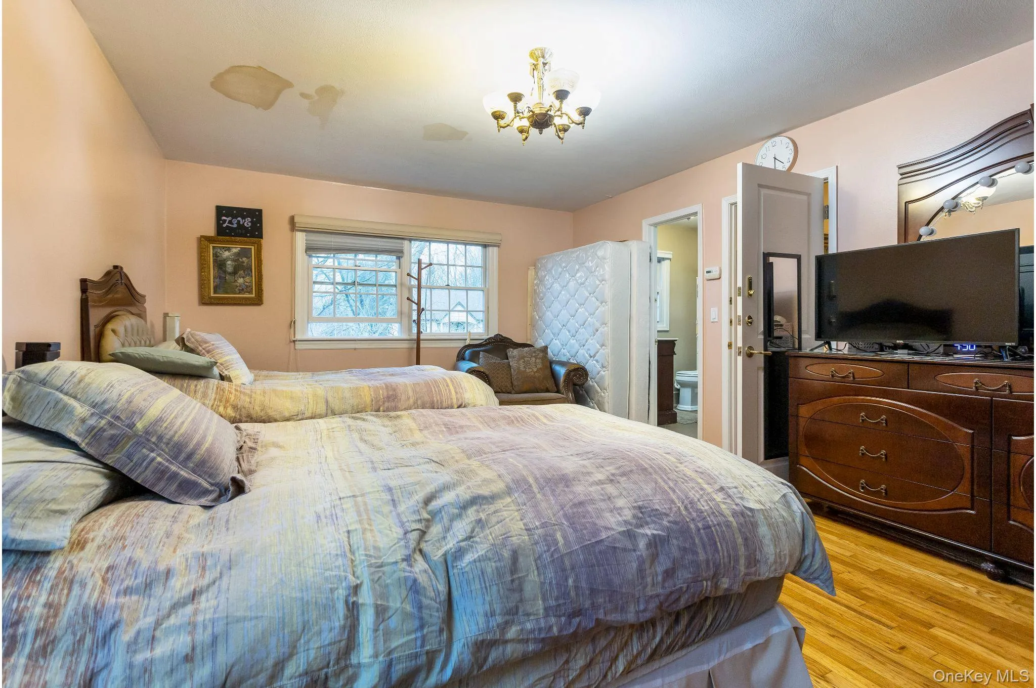 Bedroom featuring light wood-style floors, a chandelier, and ensuite bath Bedroom featuring light wood-style floors, a chandelier, and ensuite bath