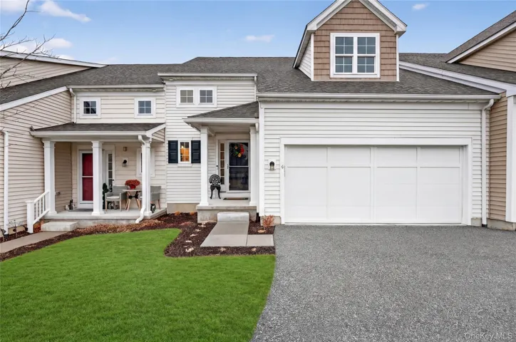 View of front of property with a shingled roof, covered porch, a front lawn, and asphalt driveway