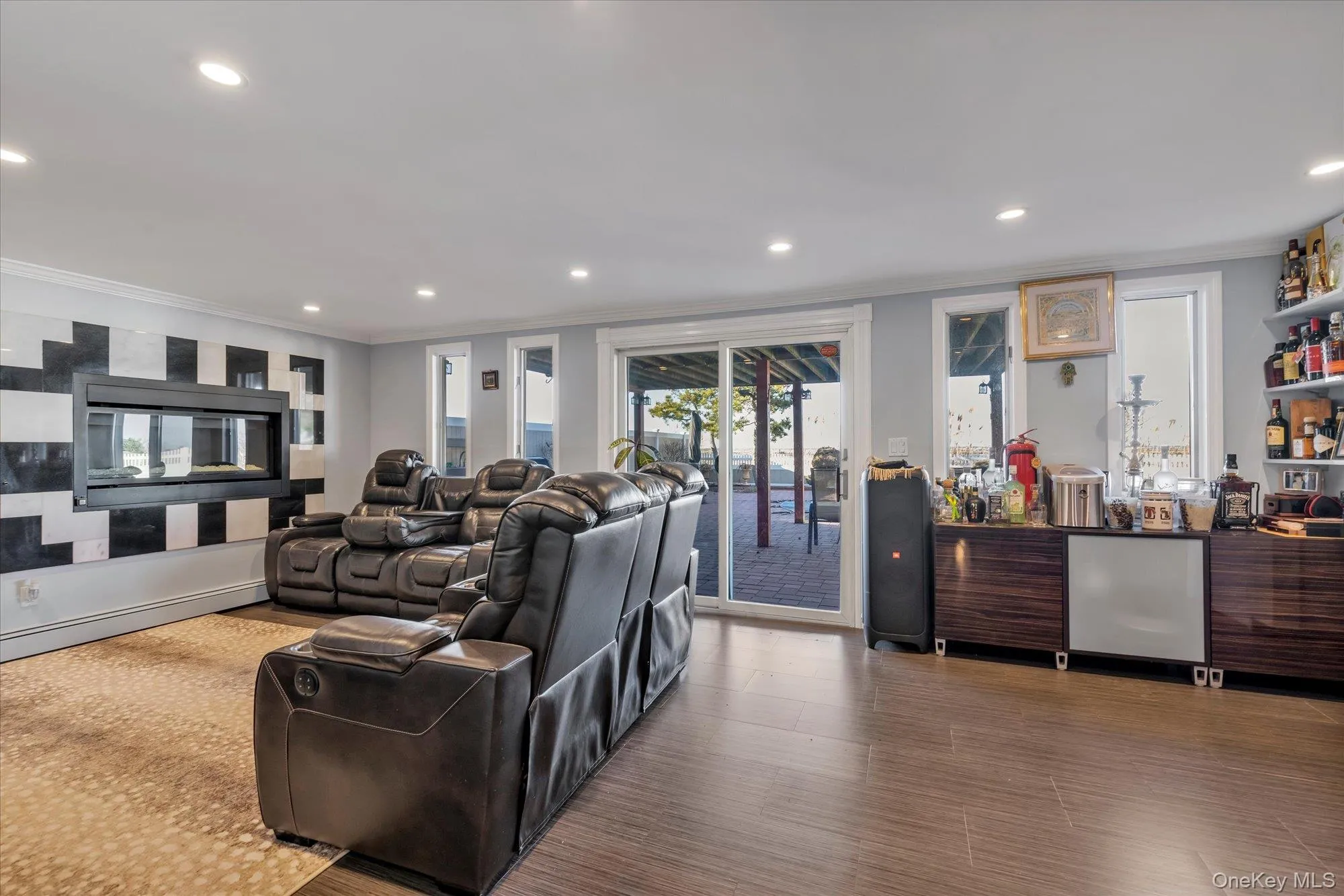Family room with doors to backyard, featuring wood finished floors, a fireplace, recessed lighting, a bar, and ornamental molding Family room with doors to backyard, featuring wood finished floors, a fireplace, recessed lighting, a bar, and ornamental molding