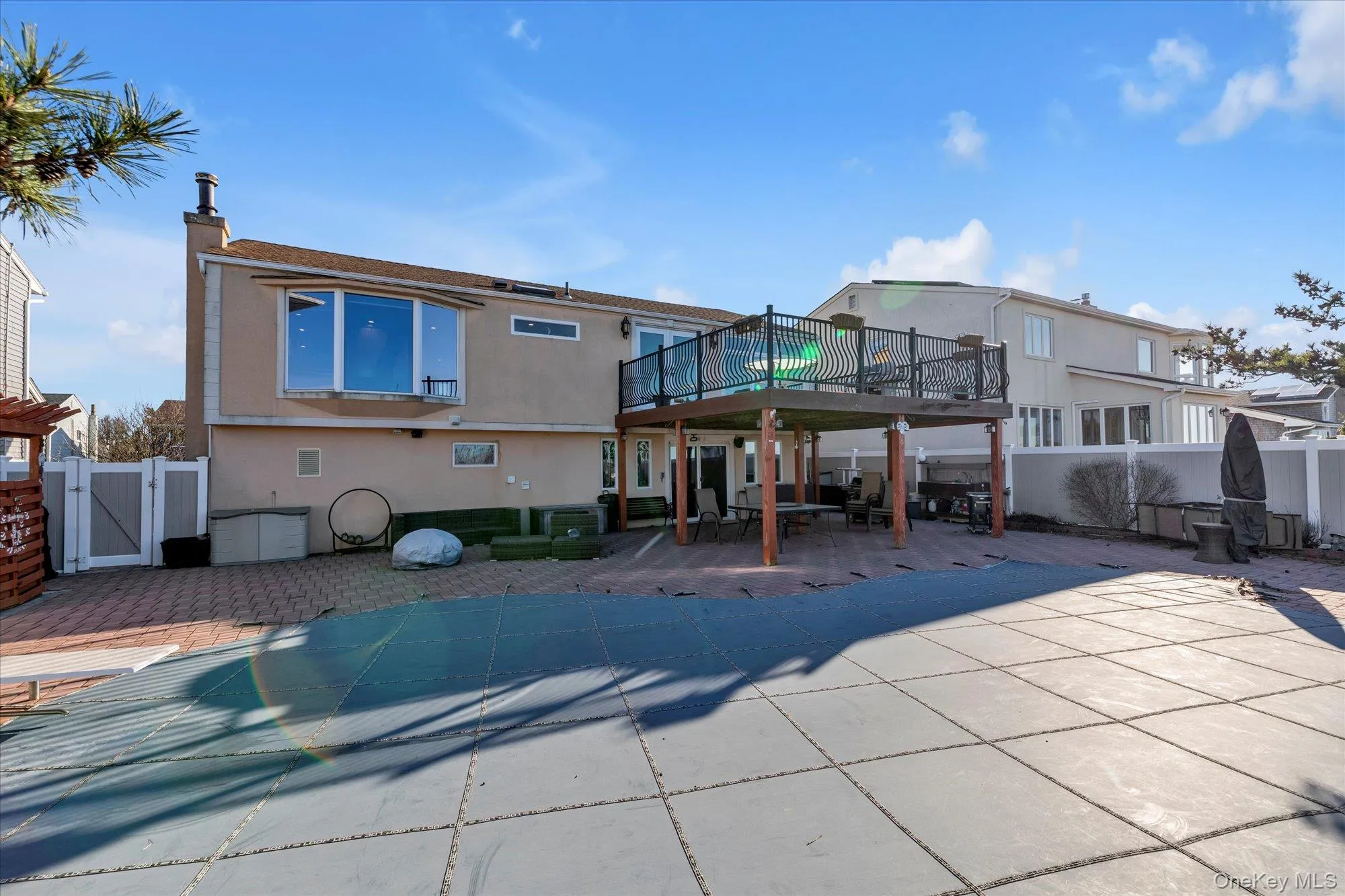 Rear view of property featuring stucco siding, a deck, a gate, a fenced backyard, and a patio area Rear view of property featuring stucco siding, a deck, a gate, a fenced backyard, and a patio area