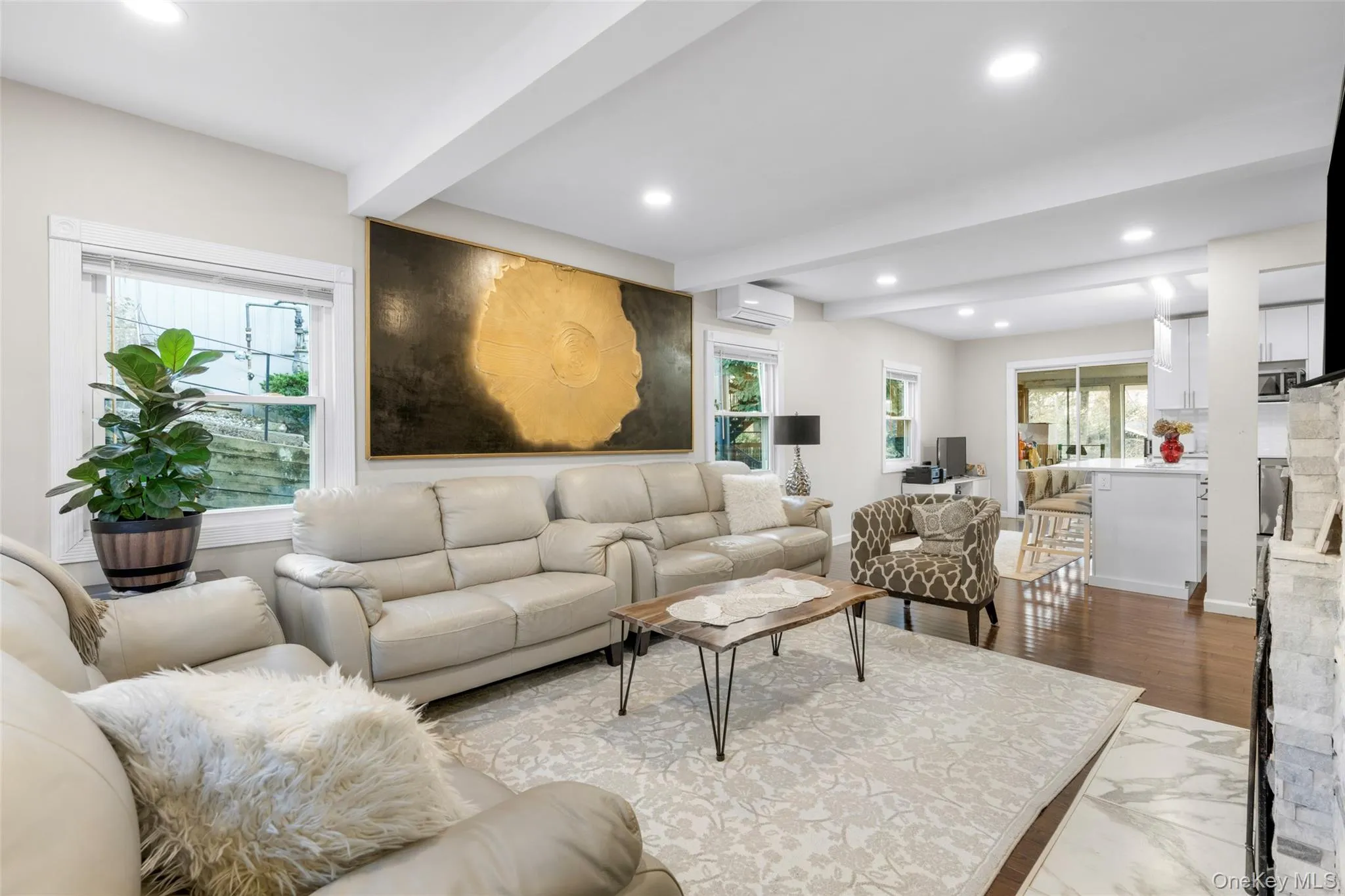 Living room featuring hardwood / wood-style flooring, a wealth of natural light, beamed ceiling, and a wall mounted air conditioner Living room featuring hardwood / wood-style flooring, a wealth of natural light, beamed ceiling, and a wall mounted air conditioner
