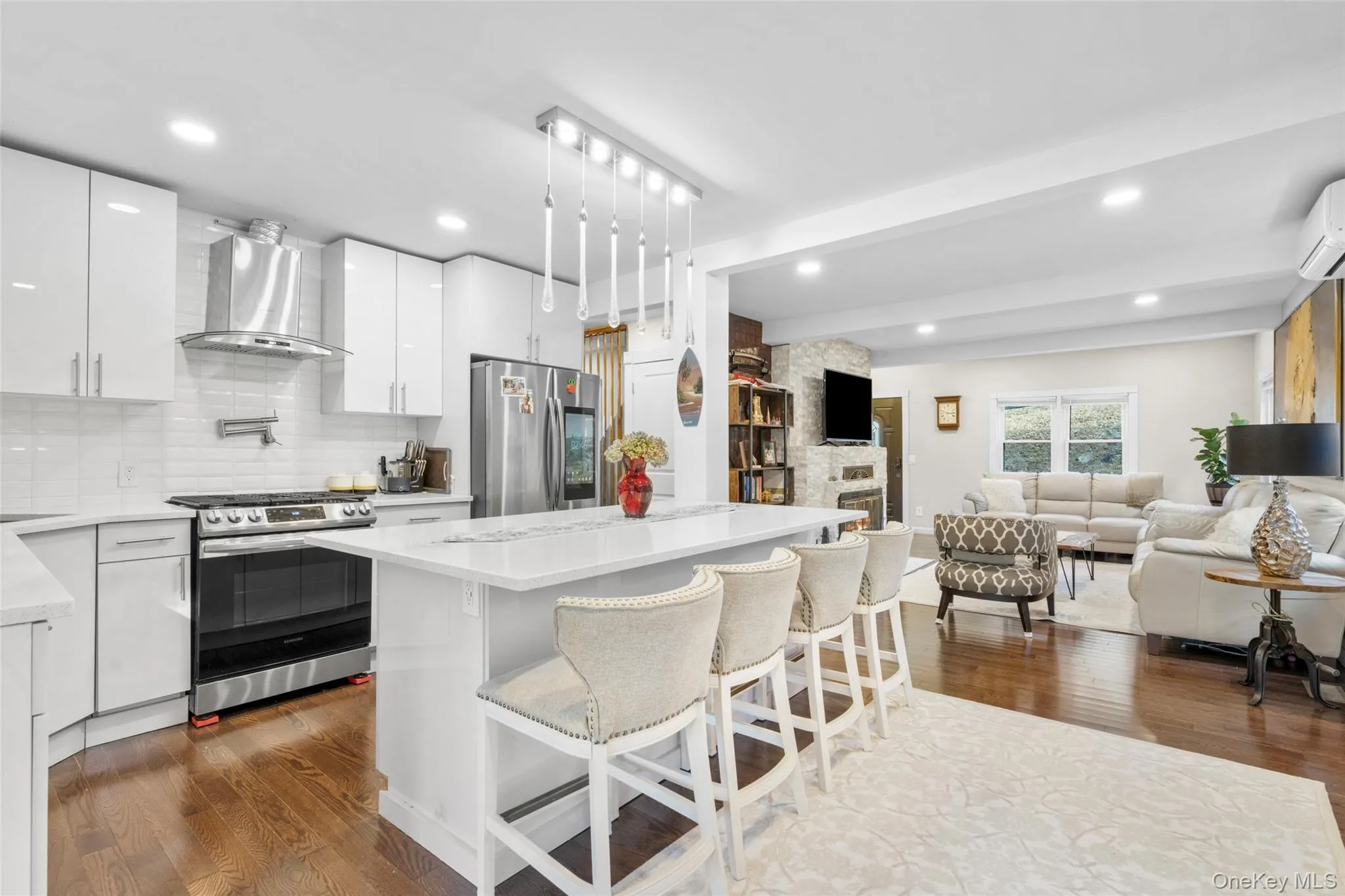 Kitchen featuring a kitchen breakfast bar, white cabinetry, appliances with stainless steel finishes, and wall chimney exhaust hood Kitchen featuring a kitchen breakfast bar, white cabinetry, appliances with stainless steel finishes, and wall chimney exhaust hood
