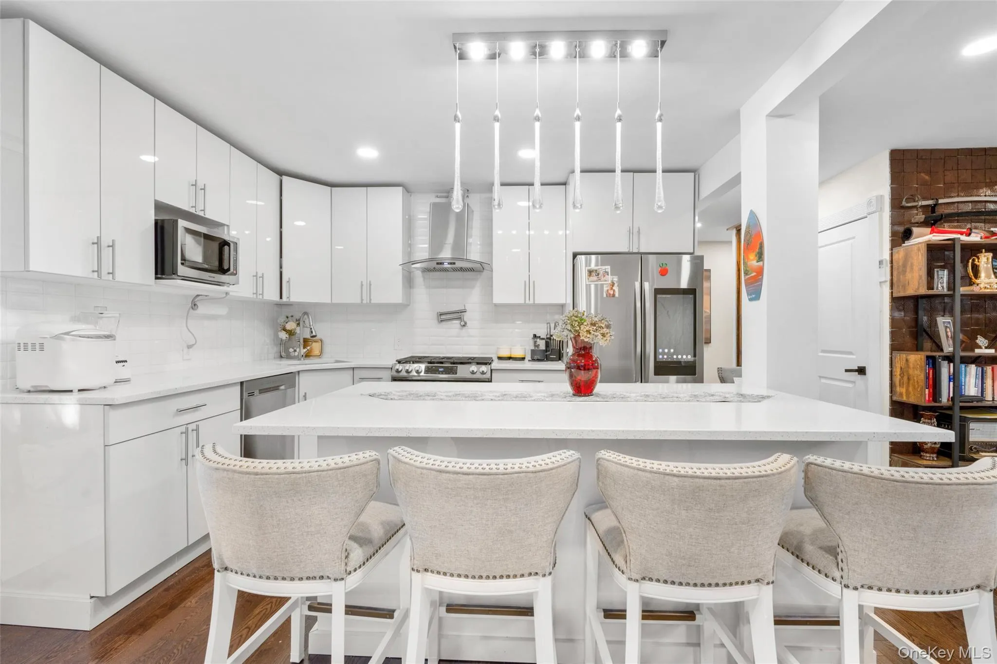 Kitchen featuring white cabinets, appliances with stainless steel finishes, wall chimney range hood, and a kitchen island Kitchen featuring white cabinets, appliances with stainless steel finishes, wall chimney range hood, and a kitchen island