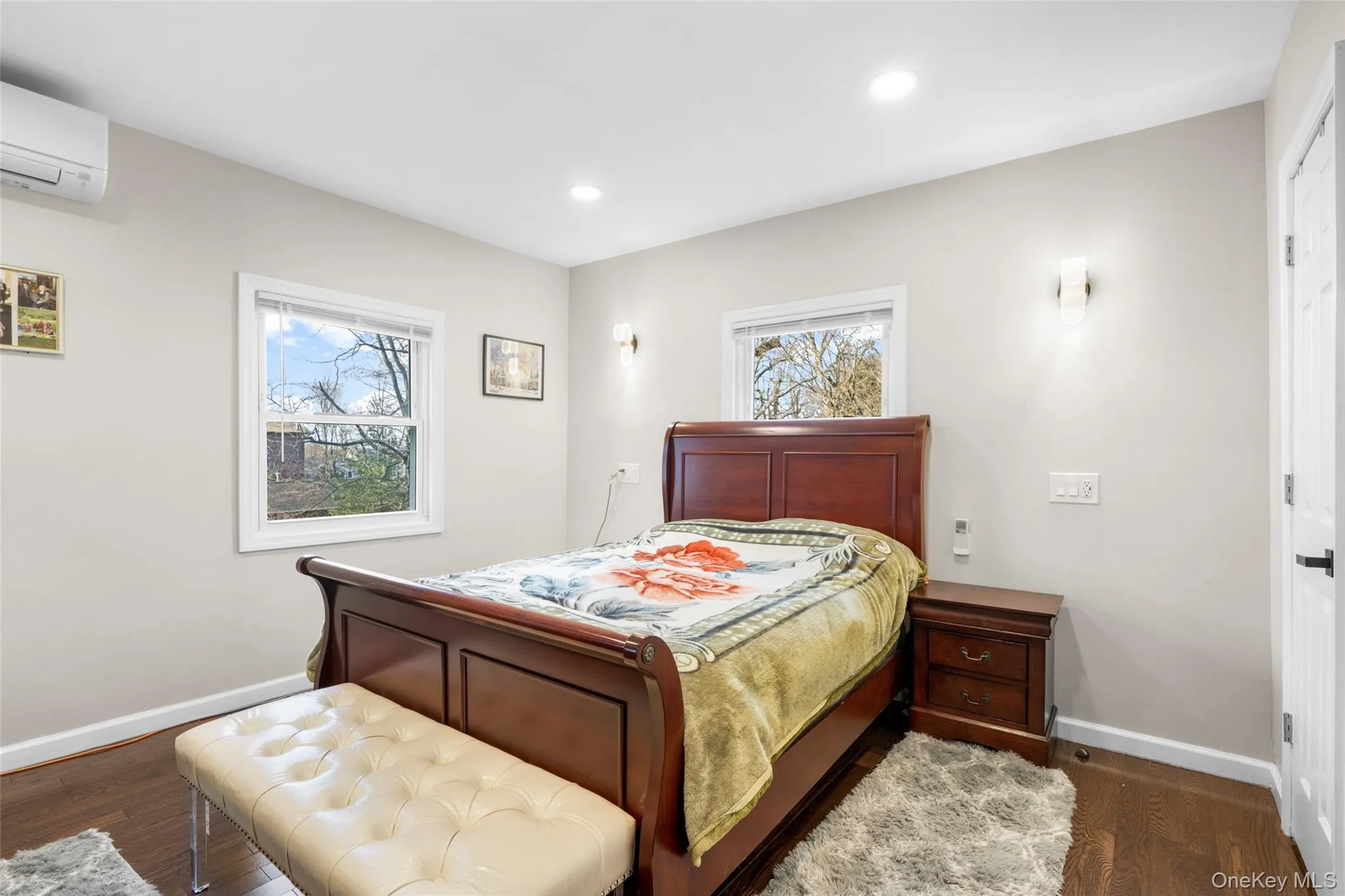 Primary bedroom featuring a wall unit AC and dark hardwood / wood-style floors Primary bedroom featuring a wall unit AC and dark hardwood / wood-style floors