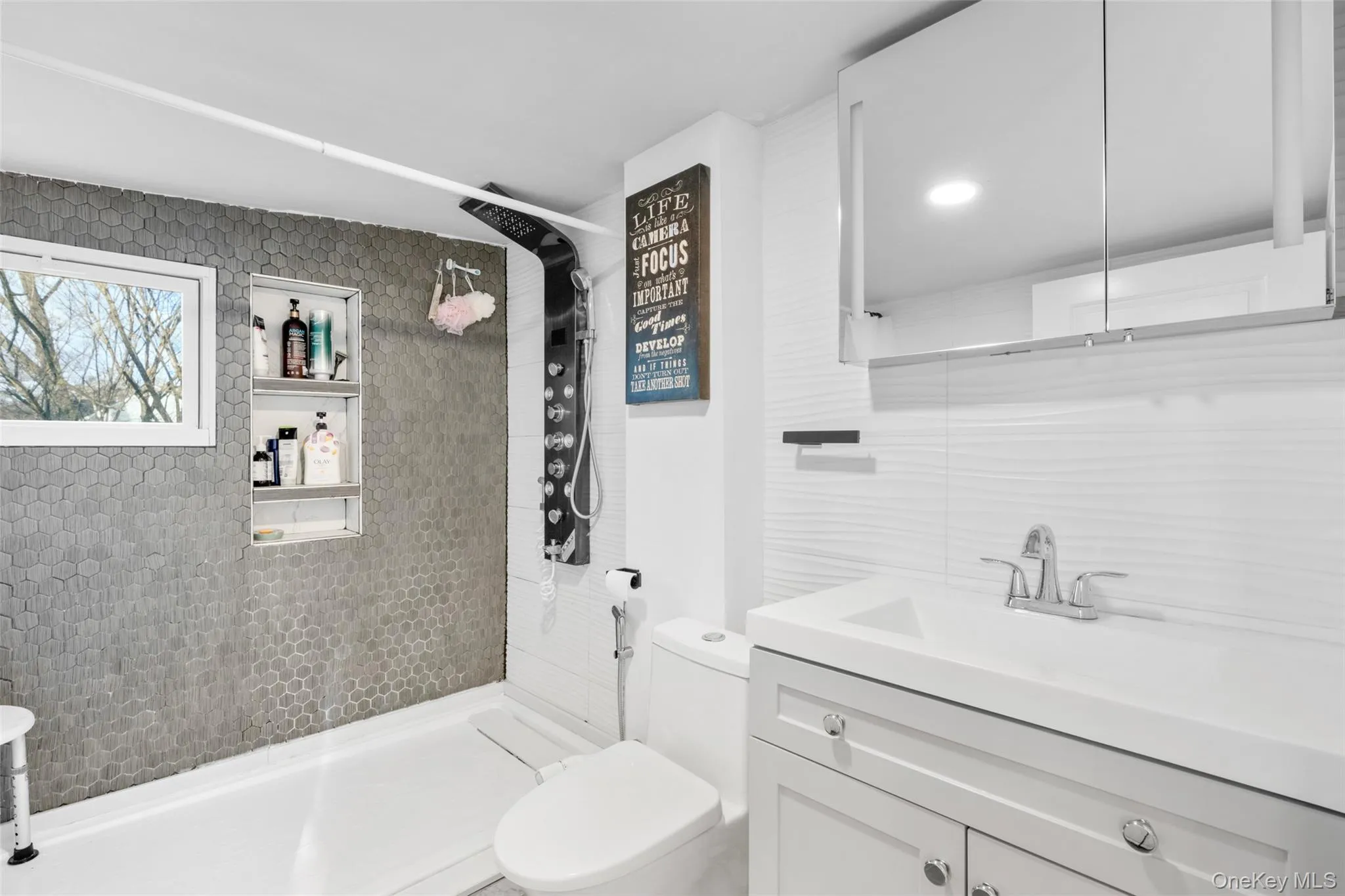 Bathroom featuring toilet, vanity, tile walls, tasteful backsplash, and a tile shower Bathroom featuring toilet, vanity, tile walls, tasteful backsplash, and a tile shower