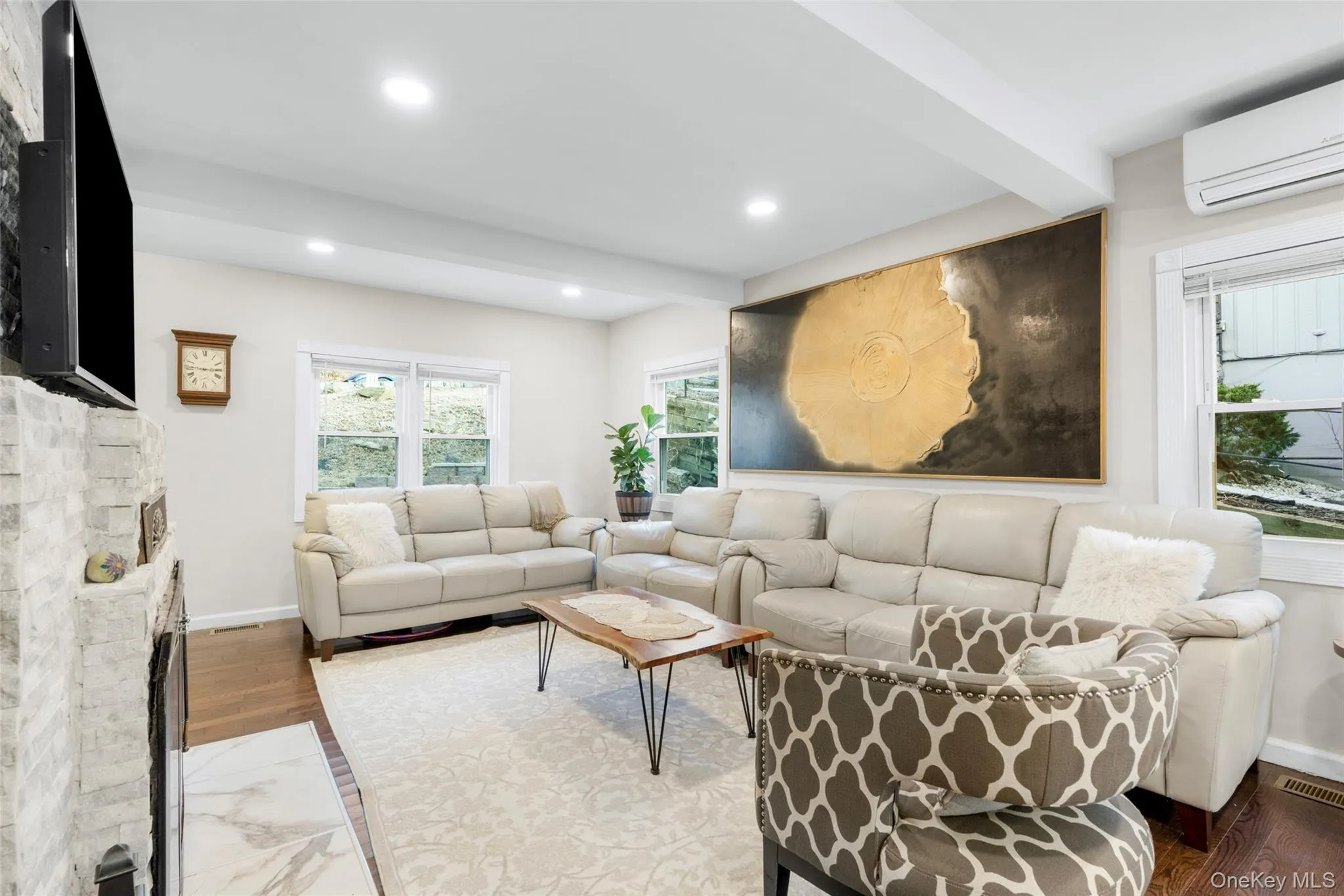 Living room with wood-type flooring, beamed ceiling, a wall mounted AC, and a fireplace Living room with wood-type flooring, beamed ceiling, a wall mounted AC, and a fireplace