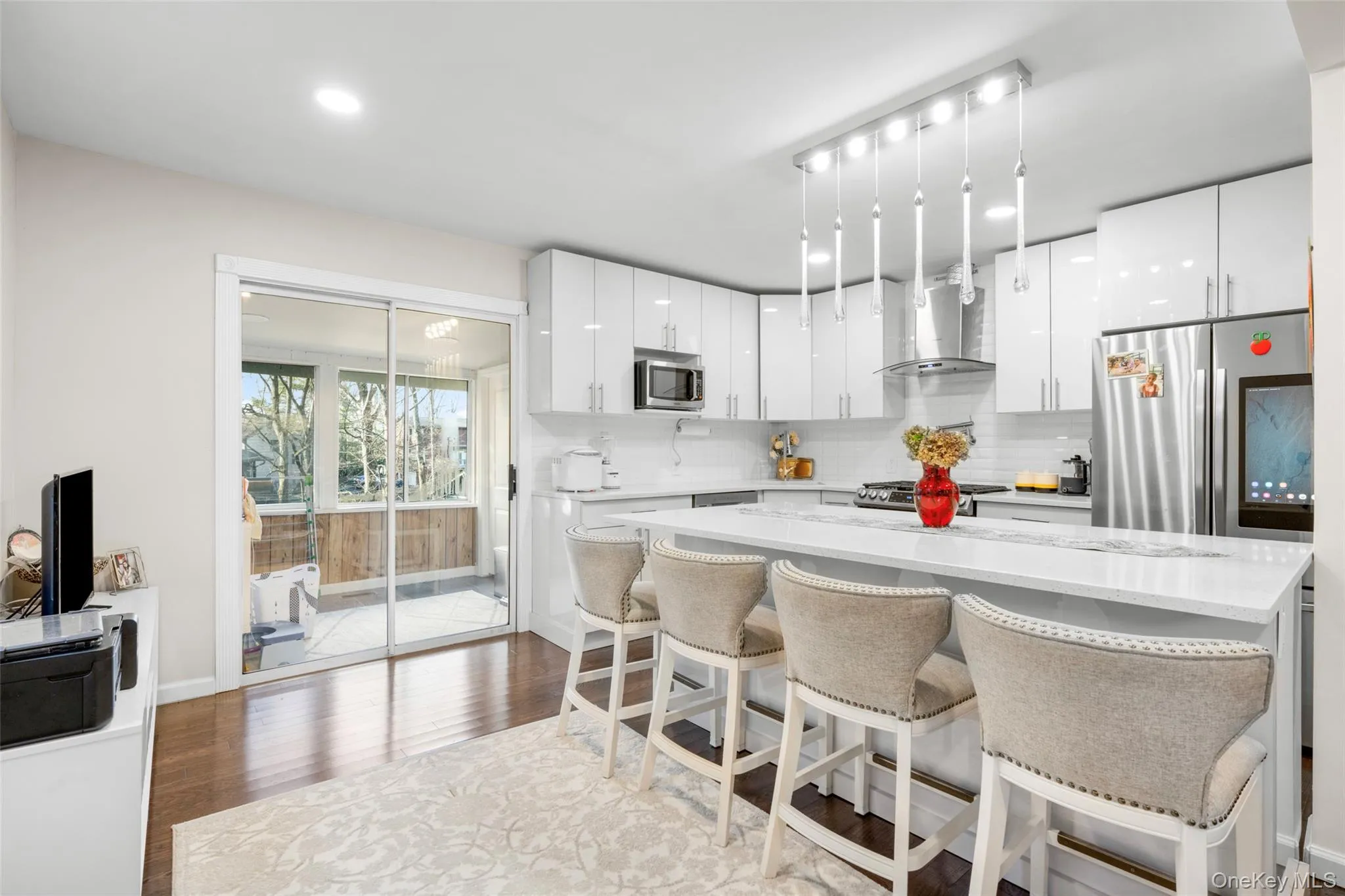 Kitchen featuring appliances with stainless steel finishes, white cabinets, tasteful backsplash, and wall chimney range hood Kitchen featuring appliances with stainless steel finishes, white cabinets, tasteful backsplash, and wall chimney range hood