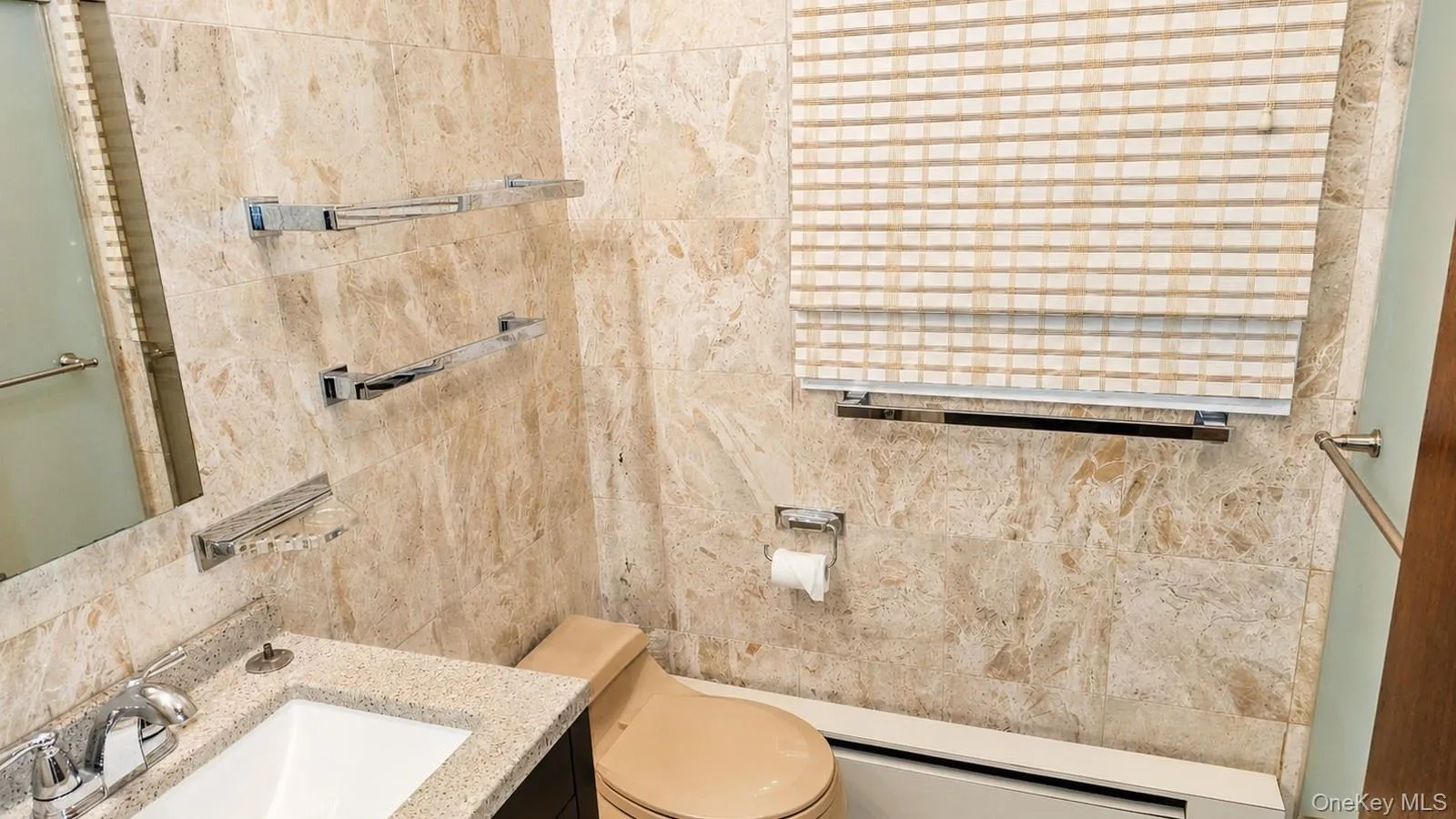 Bathroom featuring full-height stone-look wall tiling and a light-colored roller shade Bathroom featuring full-height stone-look wall tiling and a light-colored roller shade