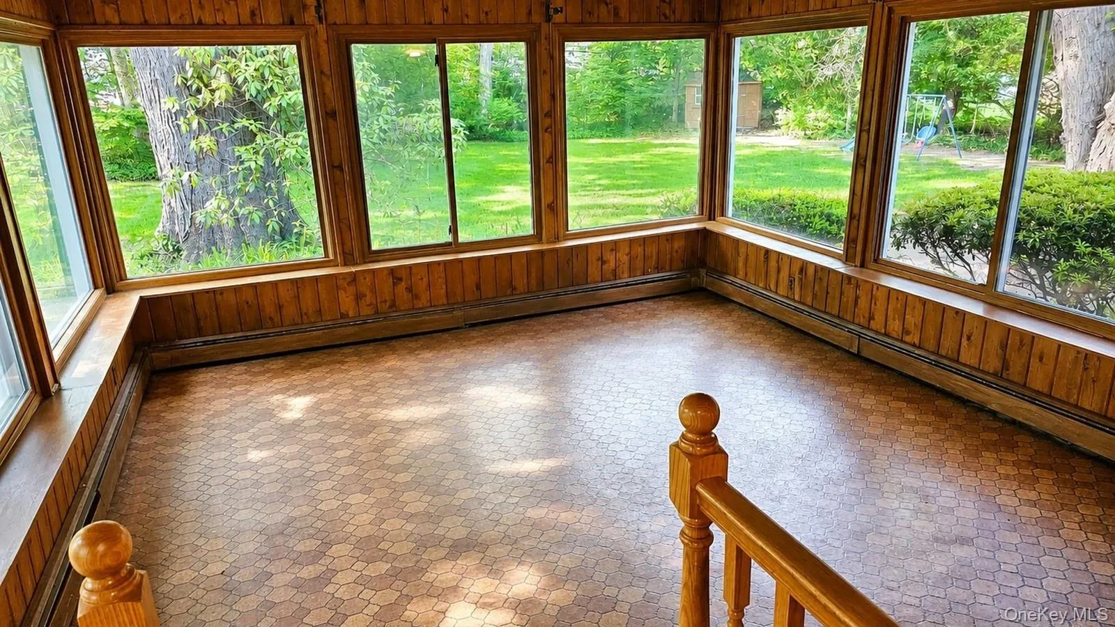 listing photo of the Sunroom at 9 Sheep Pasture Lane in Huntington, NY, showing wood paneling, large windows, tile flooring, and backyard views. listing photo of the Sunroom at 9 Sheep Pasture Lane in Huntington, NY, showing wood paneling, large windows, tile flooring, and backyard views.
