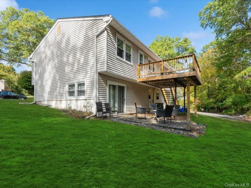 Back of house with a patio, a lawn, a wooden deck, and stairs Back of house with a patio, a lawn, a wooden deck, and stairs