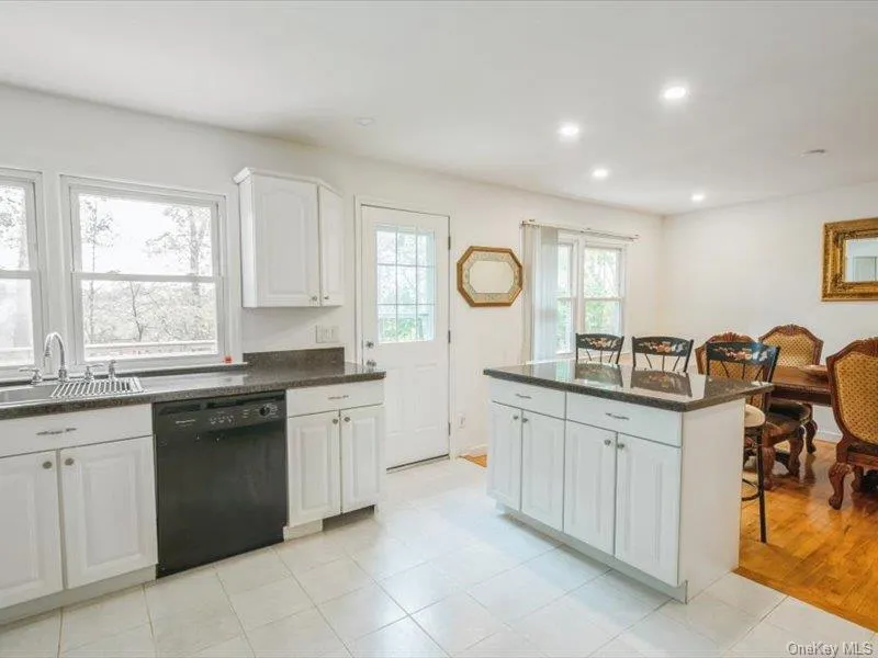 Kitchen with white cabinetry, dishwasher, recessed lighting, a center island, and light tile patterned floors Kitchen with white cabinetry, dishwasher, recessed lighting, a center island, and light tile patterned floors
