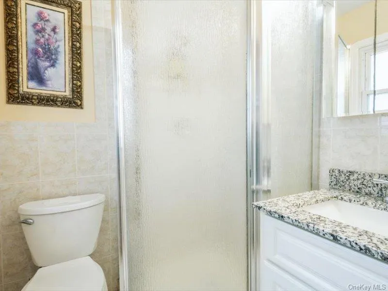 Bathroom with tile walls, vanity, and a stall shower Bathroom with tile walls, vanity, and a stall shower