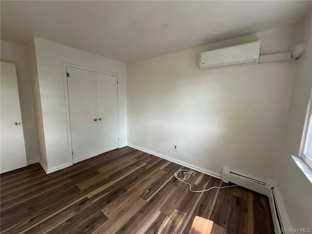 Bedroom #2 featuring dark wood-type flooring, a closet, and a wall mounted air conditioner Bedroom #2 featuring dark wood-type flooring, a closet, and a wall mounted air conditioner