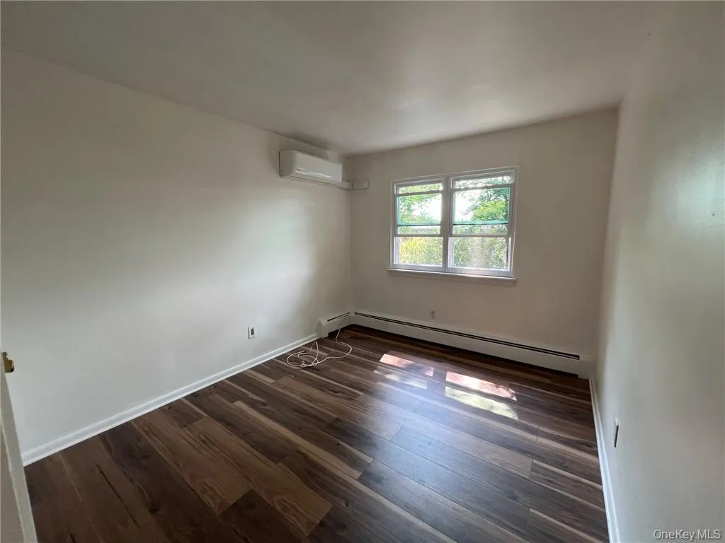Bedroom #2 room featuring a baseboard heating unit, dark hardwood / wood-style flooring, and an AC wall unit Bedroom #2 room featuring a baseboard heating unit, dark hardwood / wood-style flooring, and an AC wall unit